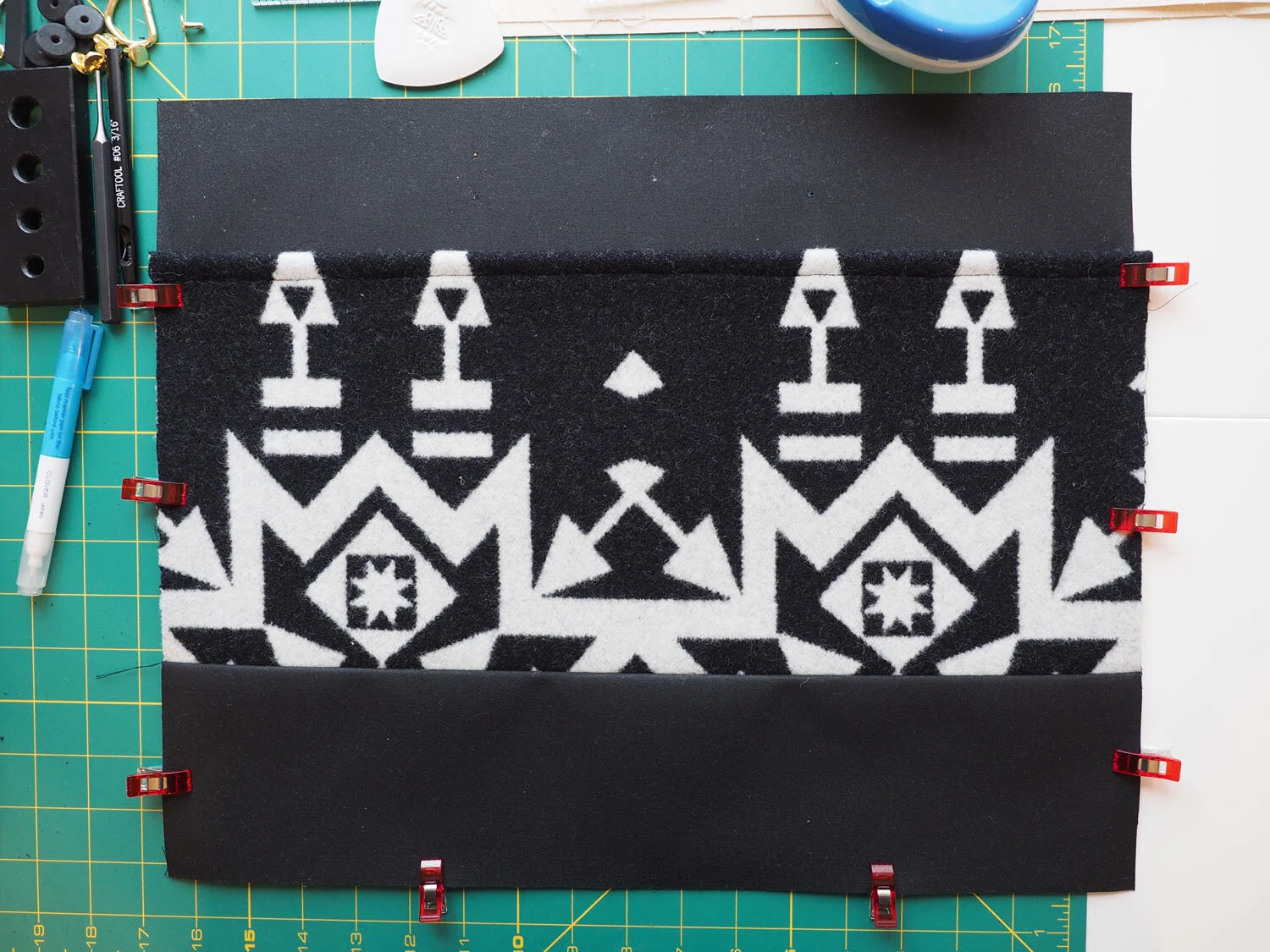  A piece of wool fabric clipped to  black waxed canvas fabric prior to being sewn 