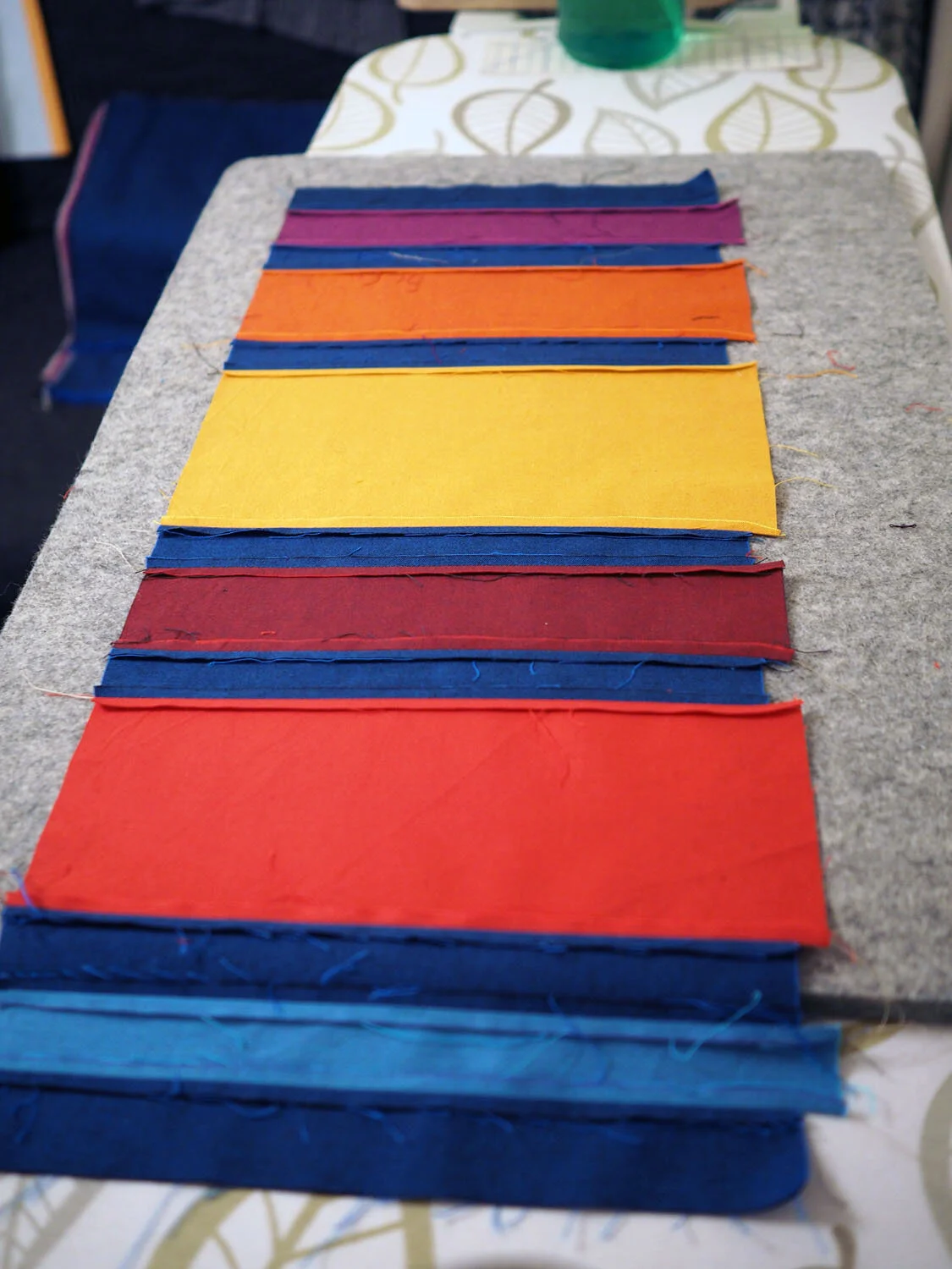 Strips of colored fabric sewn together forming a striped block of fabric 