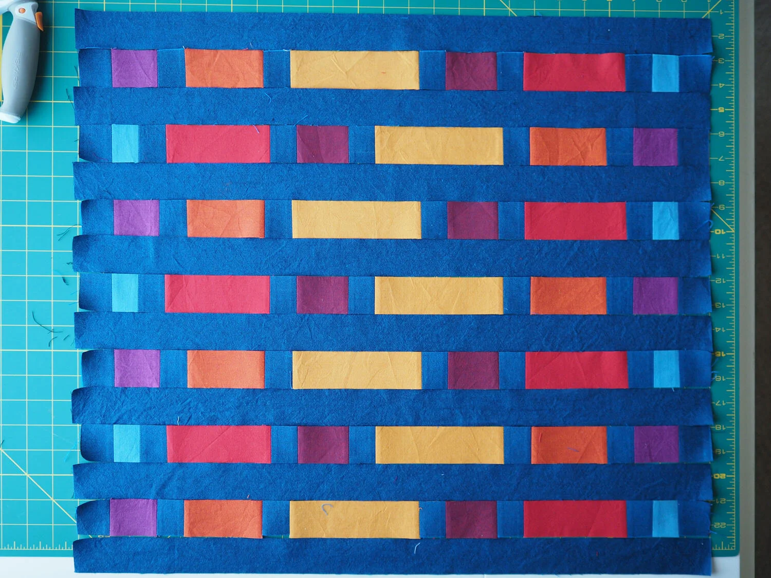  Strips of striped fabric cut from the block, positioned with long strips of navy fabric between them, waiting to be sewn together 