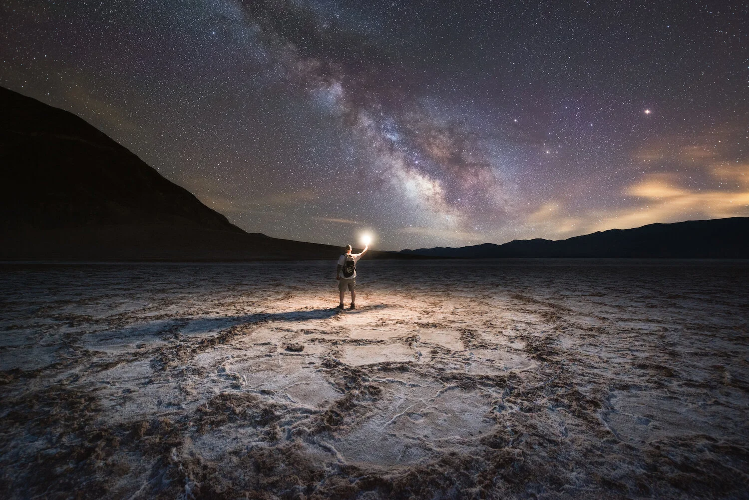 Man light painting Badwater Basin under the Milky Way Galaxy