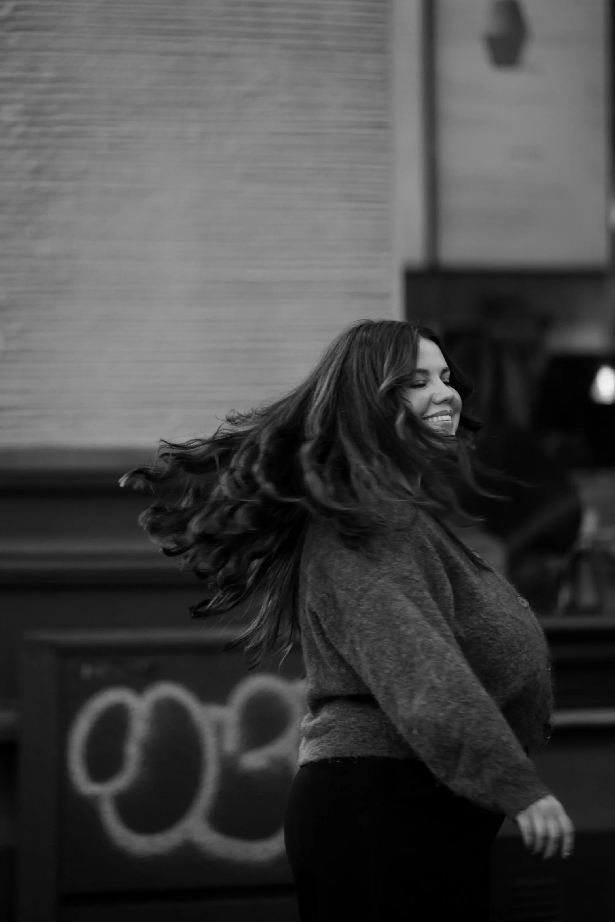 Kvinne med langt hår som snur seg og smiler, svart-hvitt bilde