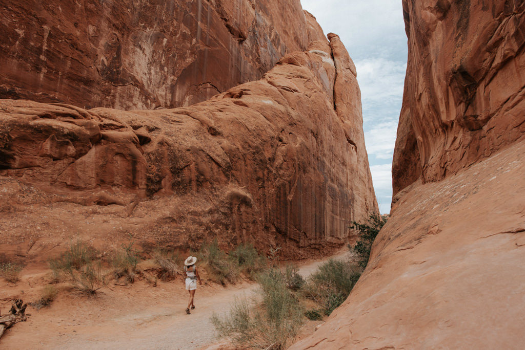 Mother wearing infant son in carrier while hiking in Arches National Park