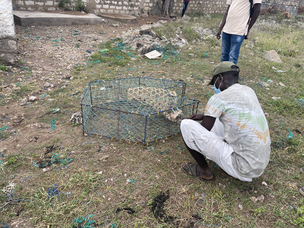 A Kenyan fisher sits in front of a modified fish trap