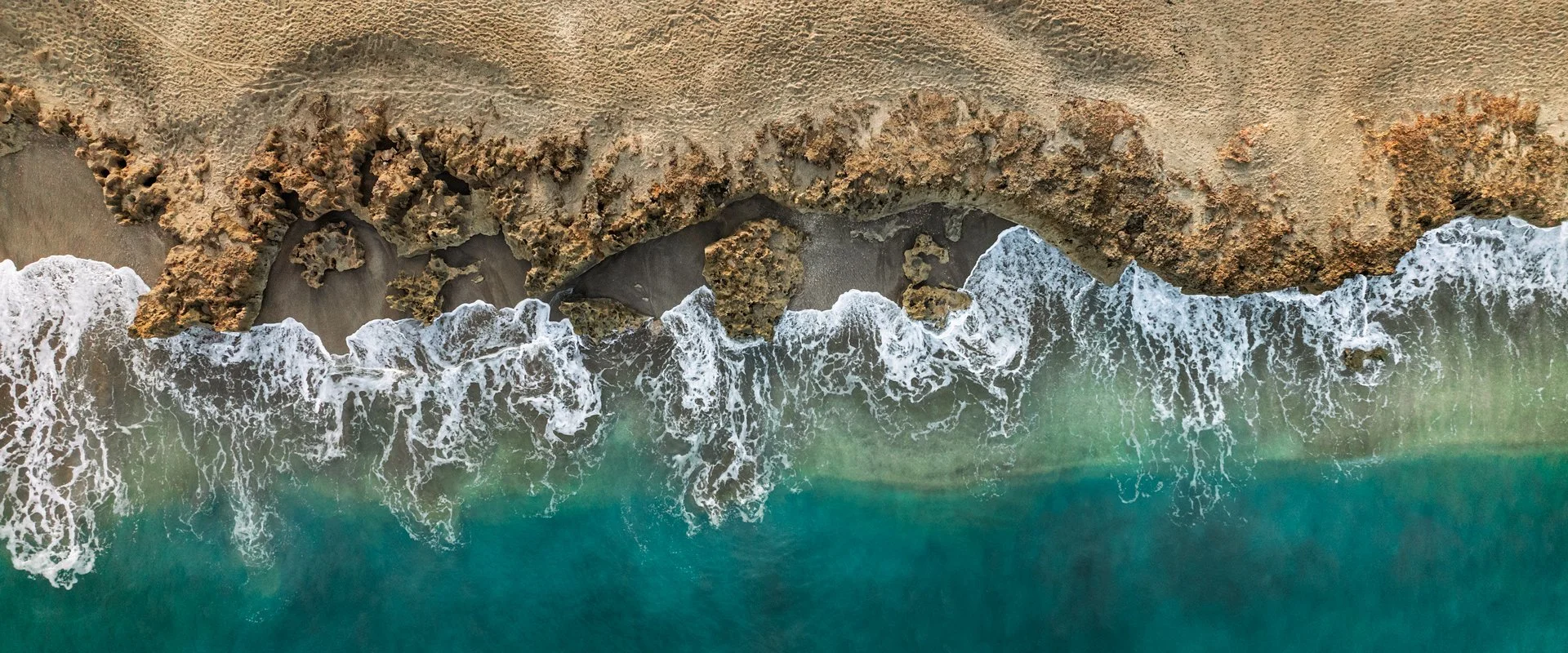 Large Aerial Photography Prints: Large panoramic print of waves crashing on the rocky beach, seen from above.
