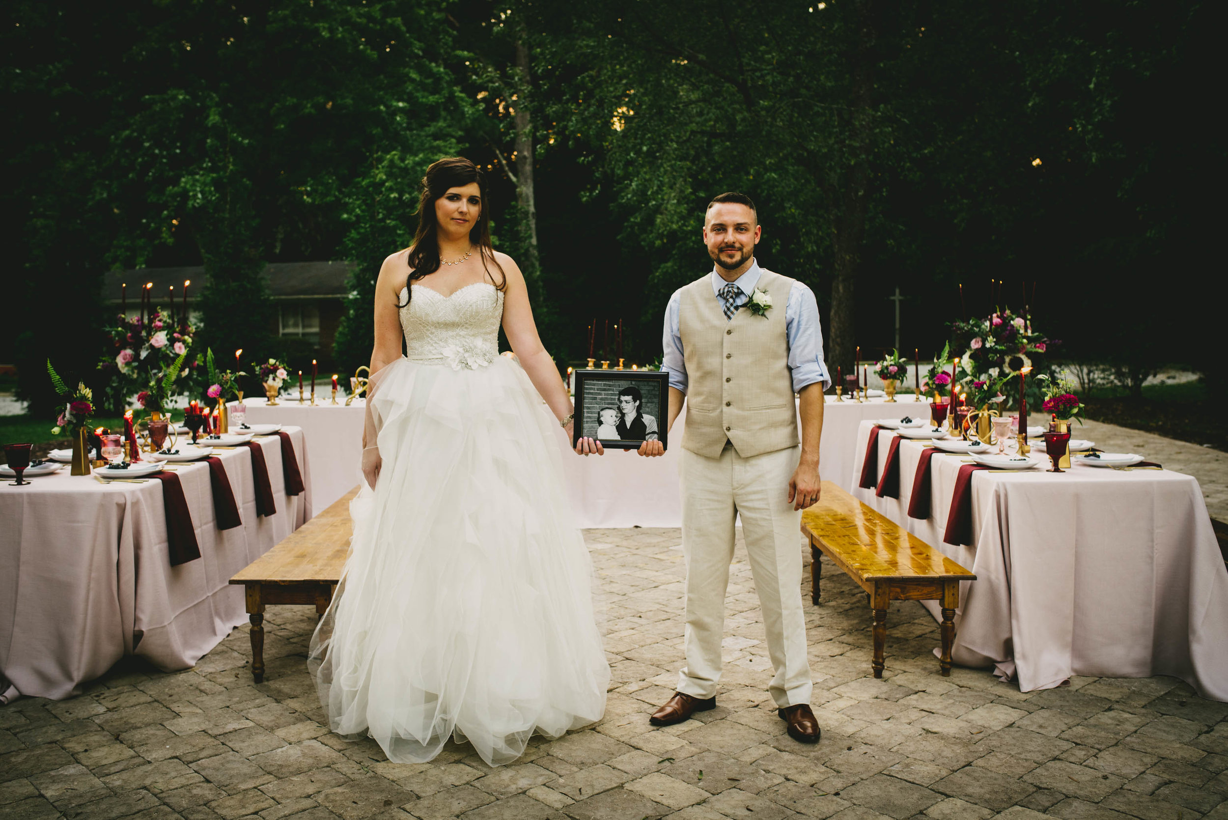 bride and groom posing with photo of grooms dad