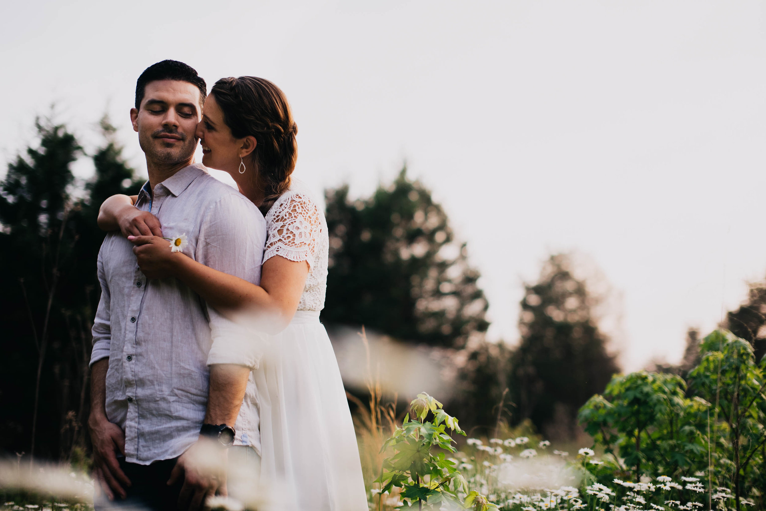 couple embracing in a field of wildflowers during their Eno River Park engagement