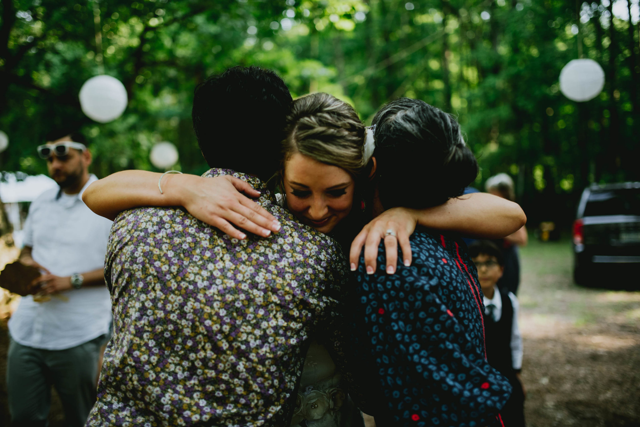 bride sharing a big hug with two wedding guests