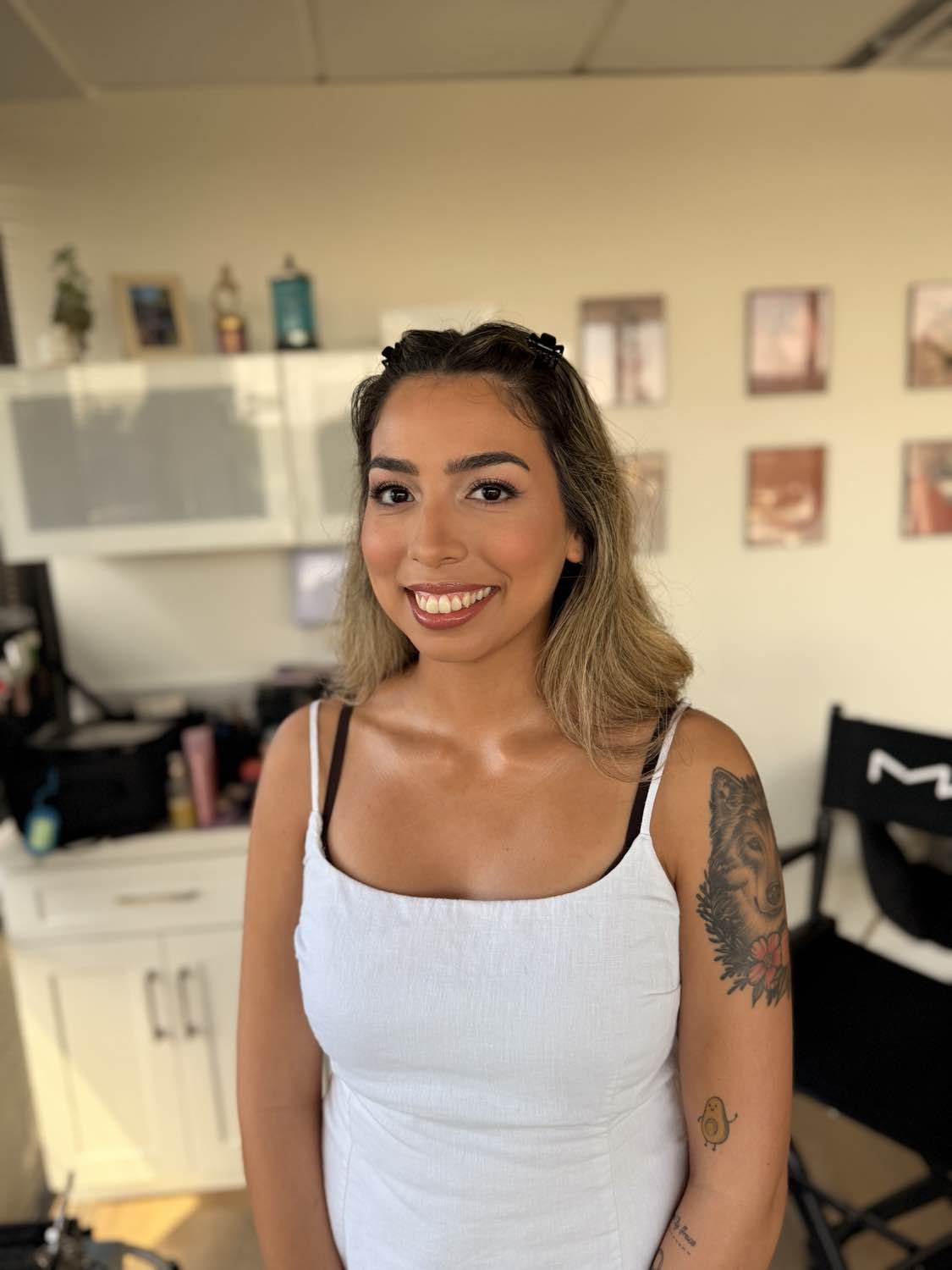 Smiling woman with shoulder-length hair and tattoos on her left arm, standing in indoor setting.