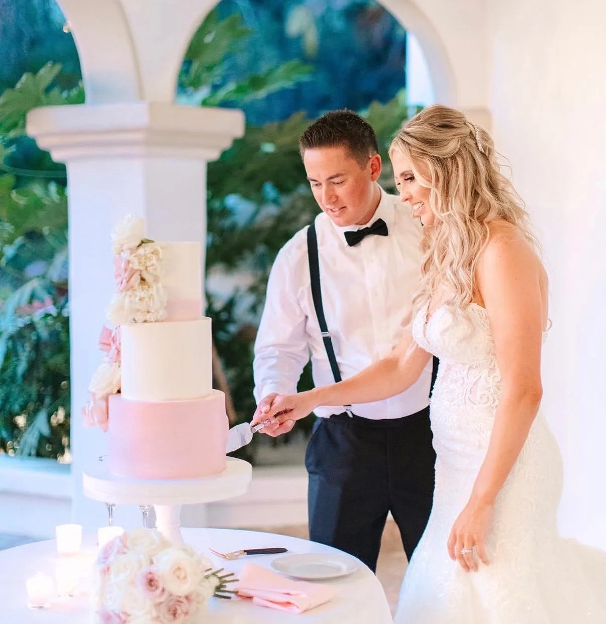 A bride and groom cutting their wedding cake together at a reception.