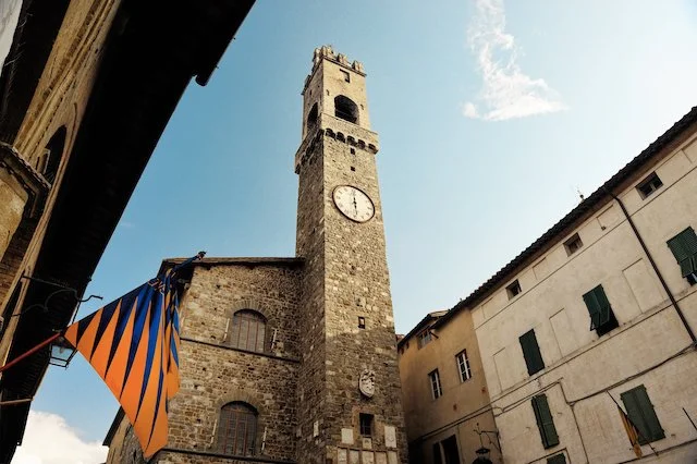 Historic Italian town square with stone clock tower, reflecting regional Italian wine heritage
