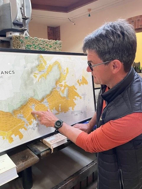 Olivier Bonville pointing to the Belles Voyes single vineyard on a Côte des Blancs Champagne map at Domaine Franck Bonville in Avize