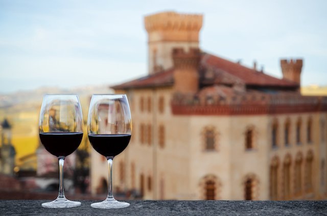 Two glasses of Barolo wine on a windowsill in front of an Italian basilica.