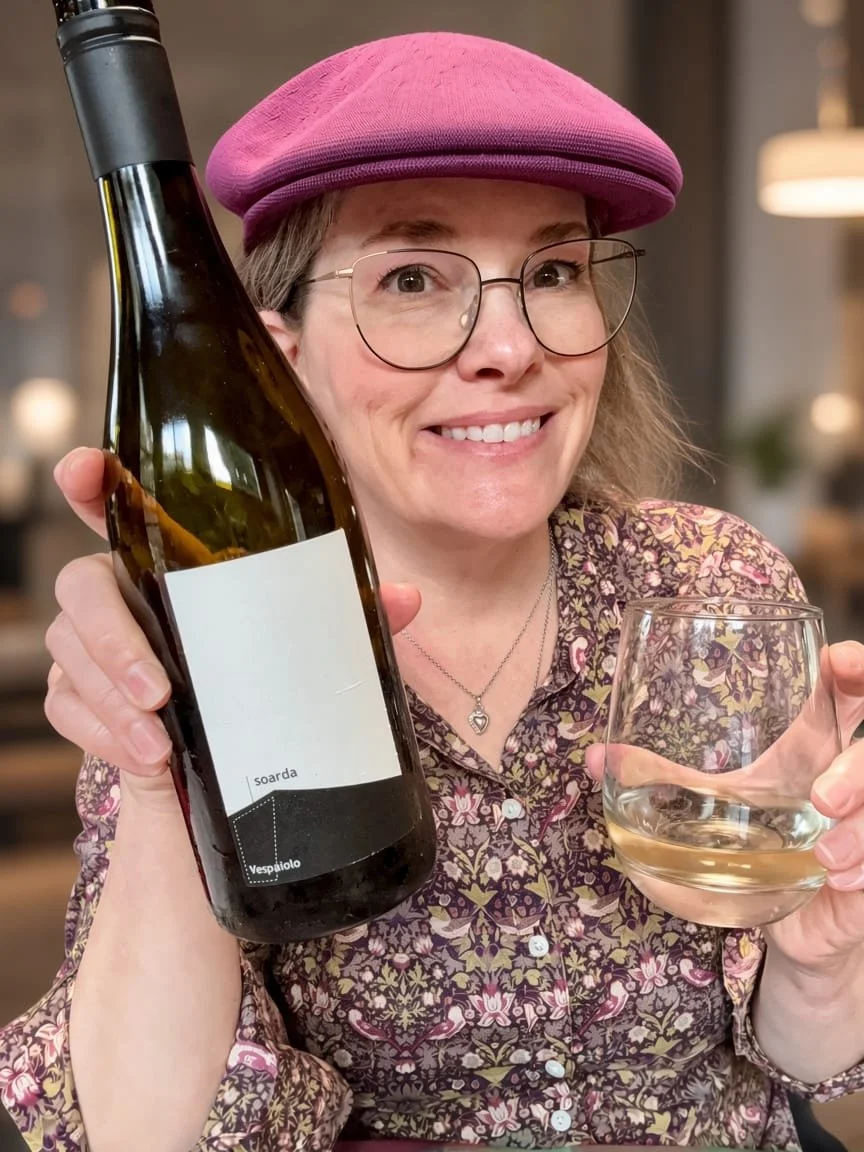 Kerry Kennell of K&L Wine Merchants holding a glass and a bottle of Italian white wine