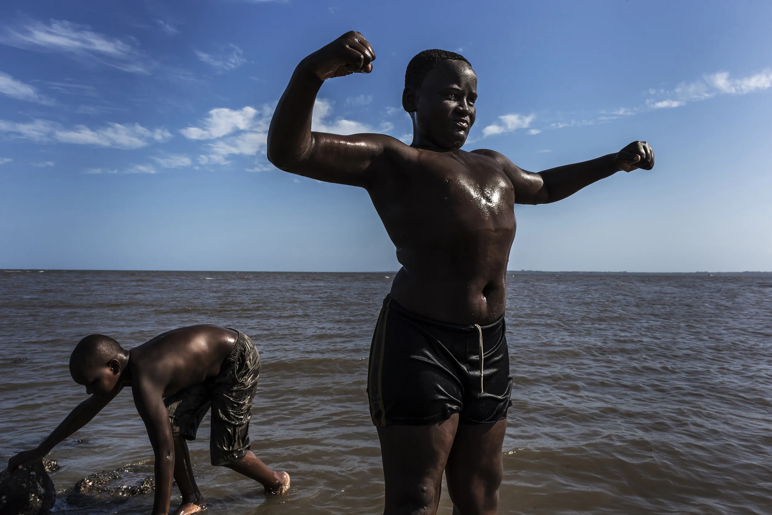 MAPUTO, MOZAMBIQUE, 23 NOVEMBER 2013: Young boys clown around posing as strongmen, Maputo beachfront, Mozambique.