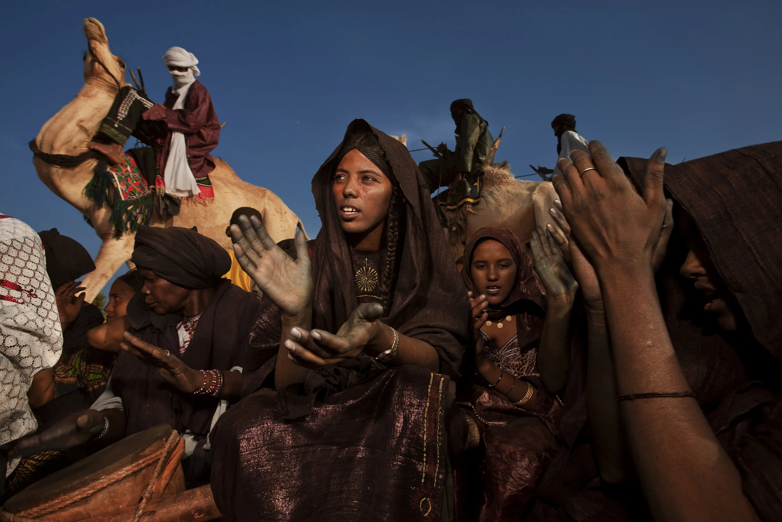 INGAL, NIGER, OCTOBER 2009: Scenes at a Baptism in a Tuareg Nomad camp, Ingal Region, Niger, 11 October 2009. Tuareg Baptism is very simple, three names are discussed by elders and then straws are drawn to choose the final name. The women perform a ritual of walking around the tent in a line with the leading woman brandishing two knives to symbolically cut away misfortune from the future of the child. The women then dance and sing and play the drums while men prepare goat mead and drink tea and discuss things while people visit from the surrounding nomad camps. Tuareg Nomads have two traditional priorities, their animals and access to water. This group has moved to this region at this time to enjoy the remaining good grassland of the rainy season and will soon move again to be close to a good water source. The nomads survive on a diet of millet and camel milk which is occasionally supplemented by goat meat. (Photo by Brent Stirton/National Geographic.)