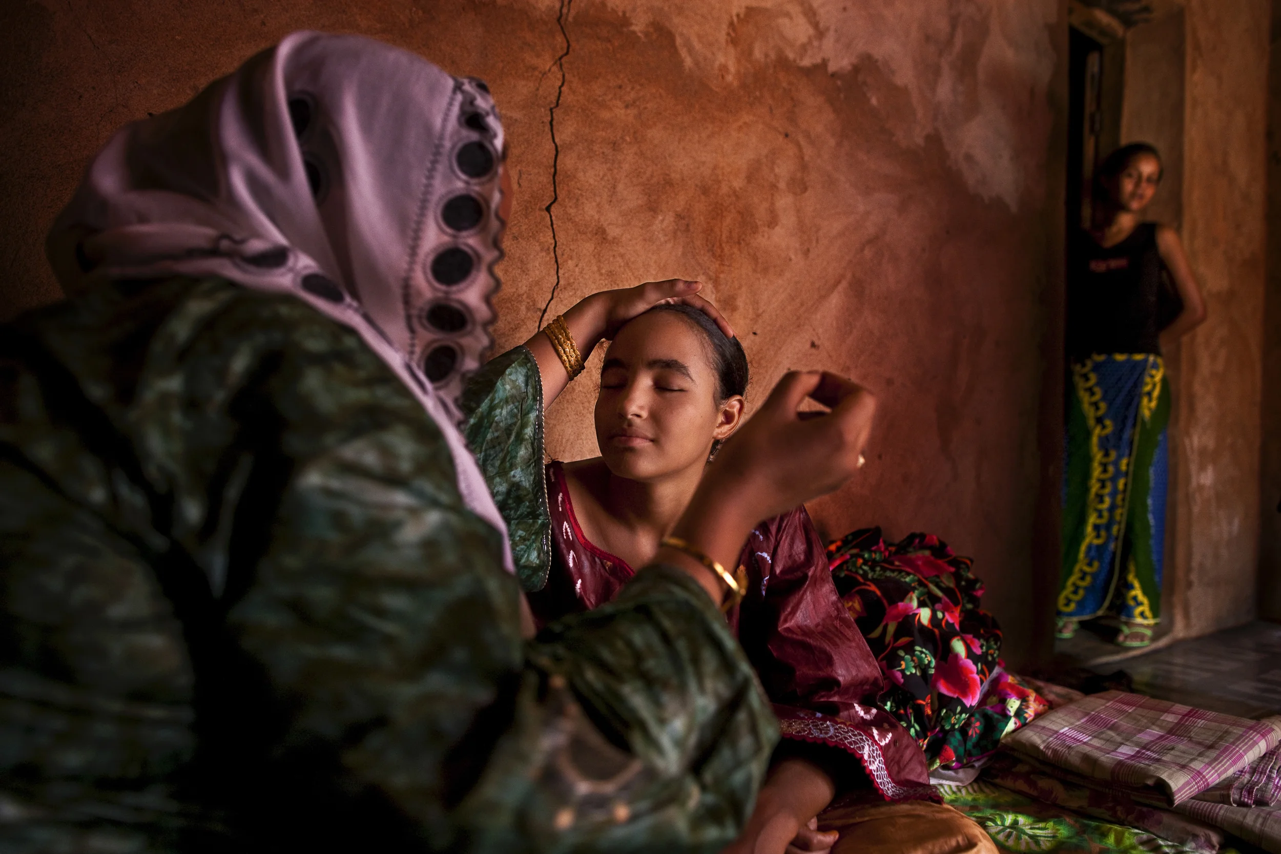 TOUWA, NIGER, SEPTEMBER 2009: A young Tuareg girl, Mariam Francois Acosta, 17, a girl descended from mixed Tuareg French blood, prepares for her wedding in the Niger city of Touwa, Spetember 25 2009. She is tended by the female members of her family and her friends. It is similar to a traditional wedding except for the nature of the clothing which is worn. She is dressed and made up, a meal is eaten, there is dancing with a Tuareg band on electric guitars, everyone goes to the Mosque at 3pm to give thanks for the wedding and after that she is considered married. That evening a party is thrown with more music and dancing. The bride and groom do not appear together for an official nuptials, it all occurs seperately. The name of the groom is Ibrahim Mahmoudane. (Photo by Brent Stirton/National Geographic.)