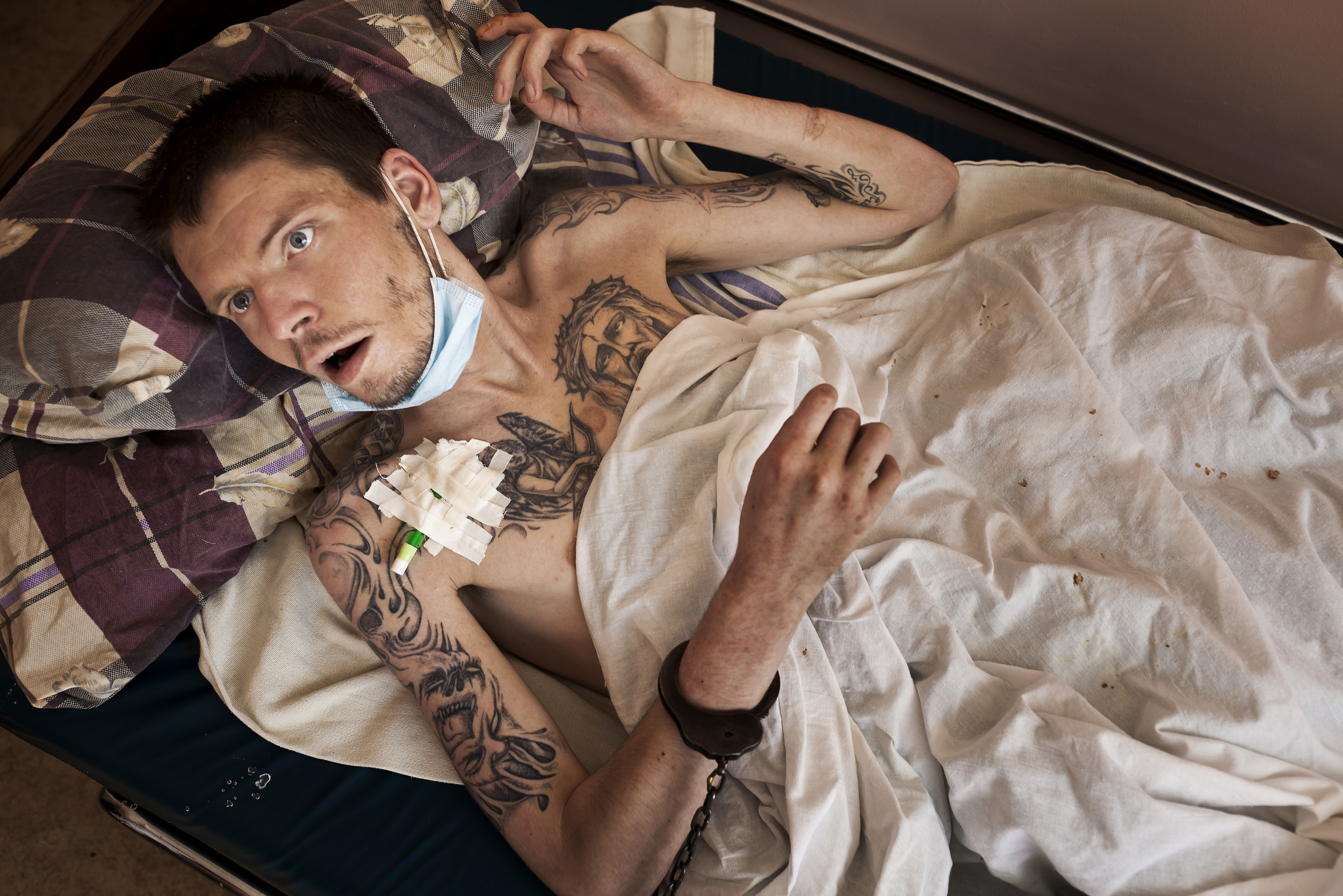 KIEV, UKRAINE, AUGUST 2011: A prisoner n the last stages of full-blown Aids who has been rushed to the Kiev Aids Center from prison receives compassionate care from a doctor while chained to the bed, The Kiev Aids Center in Kiev, Ukraine, 25 August