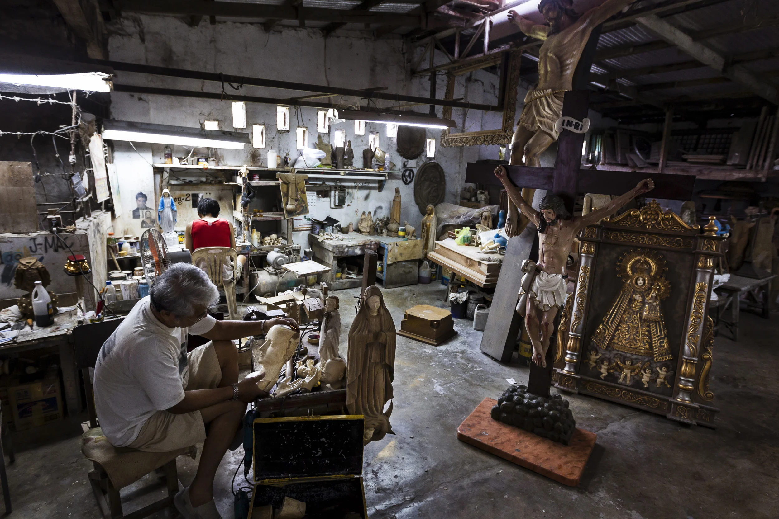 VALENZULEA, PHILIPPINES, JANUARY 2012: Master sculptor Marcial Bernales carves an Ivory head and hand set for a Catholic religious icon in his worshop in Valenzulea, close to Manila, Philippines, 25 January 2012. Bernales has been carving Ivory for 45 years and has made hundreds of pieces, all of which are of a religious nature in the Catholic faith in the Philippines. Many of these pieces are made with Ivory. His work is in the collections of many devotees and his ivory pieces are in great demand amongst the wealthy collectors of the Philippines. His workshop and workload are co-run by his wife Nene, who also runs his shop in Manila. She is a long running expert in the garments that clothe these religious icons. Their brisk trade is evidence of the demand for Ivory, they claims to use only pre-ban ivory but that is questionable given the attraction of price for ivory at 20000 pesos ($500) a kilo for raw ivory and far more for carved Benales masterpieces. It also illustrates the loophole in Ivory legislation whereby it is very difficult to tell pre-ban and post ban ivory apart. Once it is in the Philippines there are no records or statistics through which to verify claims, despite the fact that this is a centre for world ivory carving. (photo by Brent Stirton/Reportage for National Geographic Magazine.)