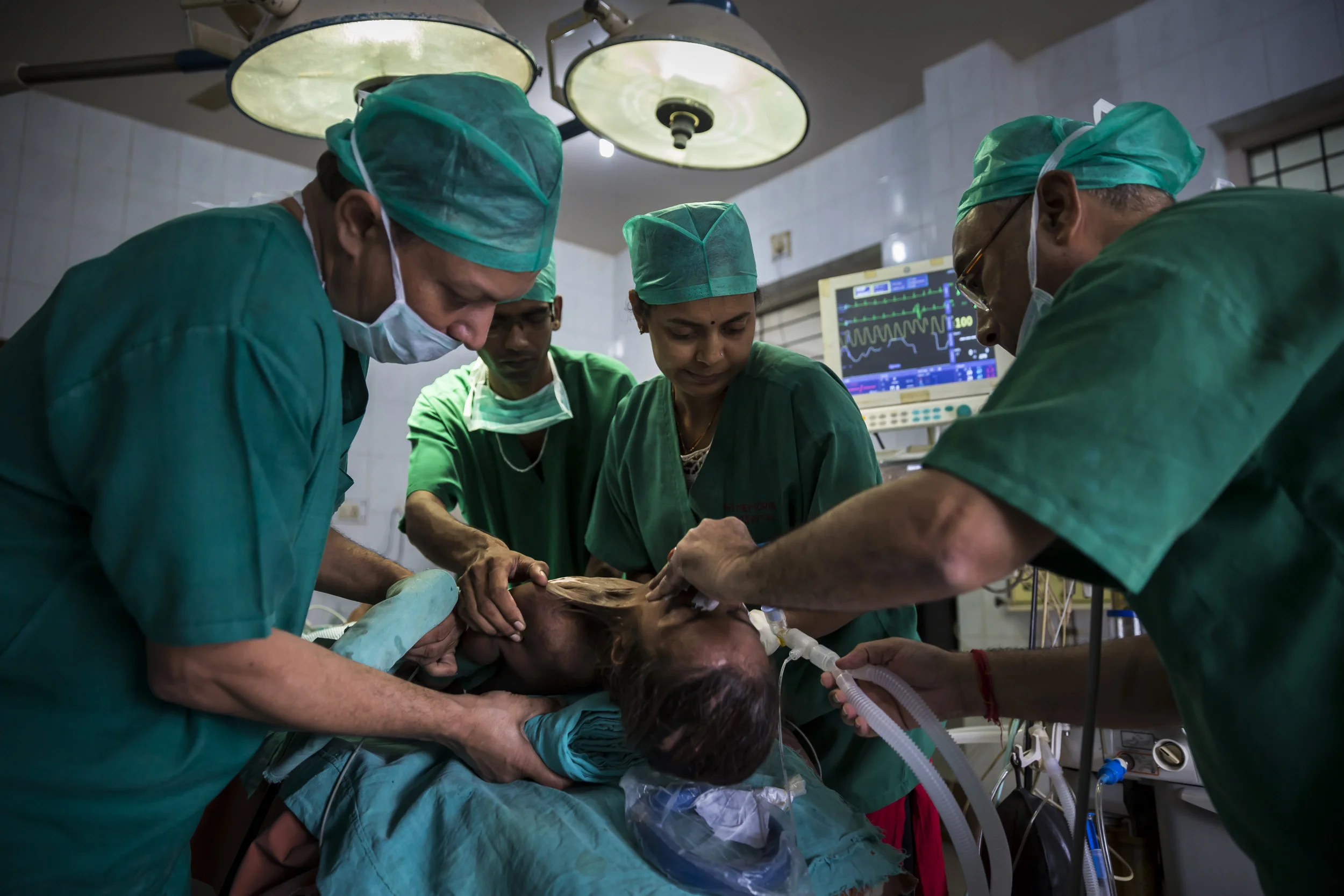 VARANASI, INDIA, 8 SEPTEMBER 2014: Renowned plastic surgeon to the poor, Dr Subodh Singh operates on burn victim Ragini Kumari, 10, who was badly burnt by a Kerosene fire when she was 2 years old, she is one of over 6 million people burnt in India every year. Ragini has suffered constrictions of her neck and shoulders and lived in a permanently cramped and restricted postion ever since. Her family is deeply impoverished and like millions of India's poor she has been unable to secure the necessary surgery. Renowned plastic surgeon to the poor, Dr Subodh Singh, found Ragini at a burns camp he held in her area and has arranged for her to attend his clinic where he performs free surgery for the poorest of the poor of India. She is seen at her home before surgery and on her journey to his clinic in Varnasi, India. (Photo by Brent Stirton/Reportage by Getty Images.)