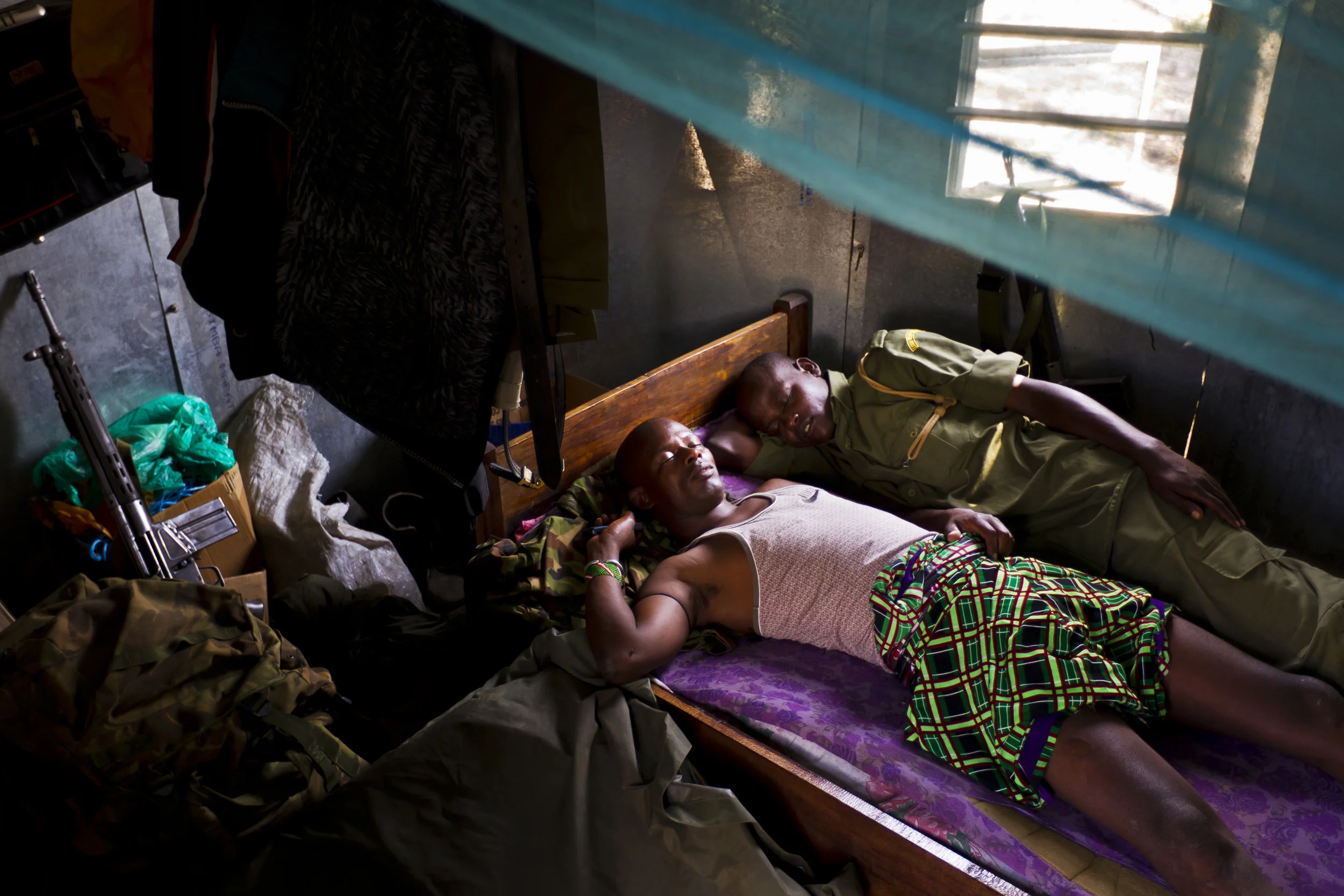 OL PEJETA CONSERVANCY, KENYA, JULY 2011: Exhausted anti-poaching team members sleep after an all-nighter on Ol Pejeta Conservancy in Kenya, 13 July 2011. The Ol Pejeta Conservancy is an important “not-for-profit” wildlife conservancy in the Laikipia District of Kenya and the largest sanctuary for black rhinos in East Africa. It is also the home of 4 of the world's remaining 8 Northern White Rhino. There has been an increase in poaching incidents on Ol Pejeta recently, in line with a massive worldwide increase in rhino poaching linked to the rise in the Asian middle class. Anti-poaching teams provide close protection to the rhino, with 24 hour observation over all rhino on Ol Pejeta and 24 hour armed guard protection over the 4 Northern White Rhino who are kept in their own Boma area. (Photo by Brent Stirton/Reportage for National Geographic.)