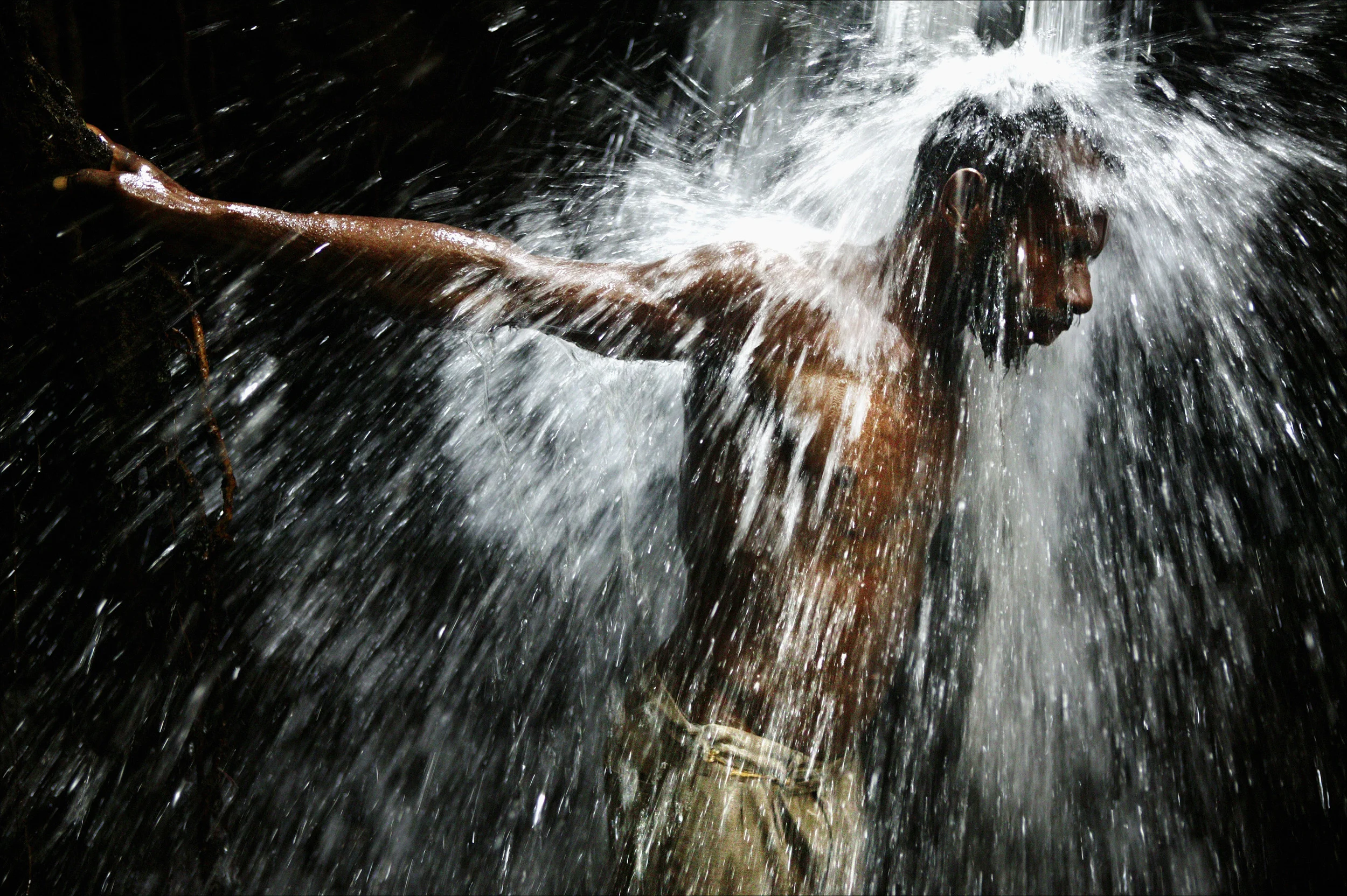 PUKAPUKI, PAPUA NEW GUINEA, AUGUST 2004: A local man showers underneath a waterfall in the rainforest close to his village in the mountains of Papua New Guinea. Traditional ways of life are under threat in Papua as villages have very little means of raising money through which to educate their children and pay medical bills. Traditional ways of life are based on sustainable farming and hunting practise. As Papuans move towards a more western lifestyle and the government attempts to raise capital for modernisation, villages are selling their natural resources such as the timber of the rainforest. This is a non-sustainable practise at this point and is having a devastating effect on water supply, traditional river routes and erosion patterns. Education as to these factors is a vital but lacking components in this transition period for Papua New Guinea. PHOTO BY BRENT STIRTON/GETTY IMAGES