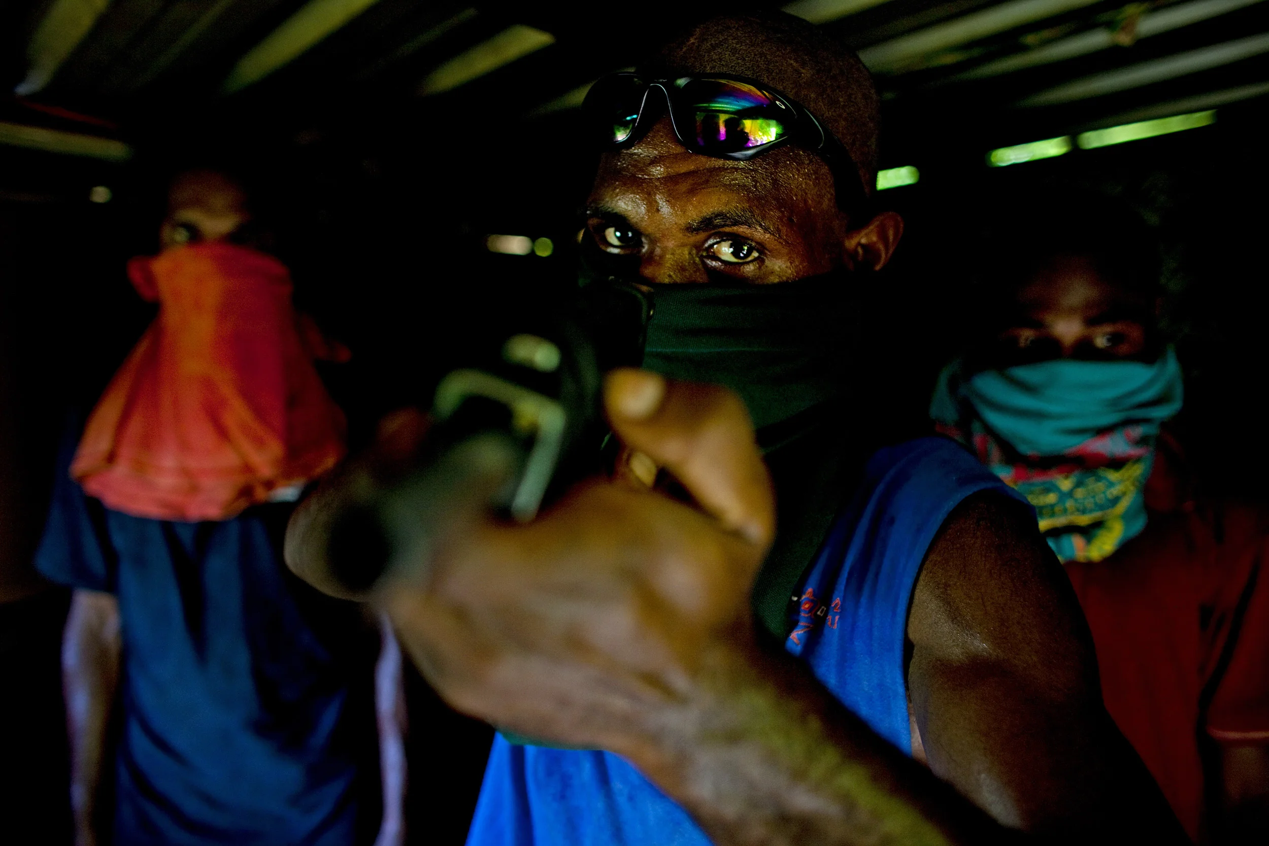EIGHT MILE SETTLEMENT, PORT MORSEBY, PAPUA NEW GUINEA-DECEMBER 2008: Four "Raskol" gang members and a hand-made gun photographed in the impoverished eight mile settlement in Port Morseby, Papua New Guinea, 23 December 2008. These "junior" gangsters carry out robberies and other criminal activities every weekend, targetting people they consider to be "Bigshots. Their only regret is the death of good friends in these robberies in shoot-outs with the police. All four boys are under 20 and have grown up in Port Morseby, the dangerous capital city of PNG. Despite growing up here and seeing first hand the progress of the city, they feel all the changes are for the worse and would like to move back to the villages where their fathers are from and farm for a living instead of the city life. None of the boys envisage giving up their "Raskol" life-style in the meantime as they see now other way to earn money in their society. (Photo by Brent Stirton/Reportage by Getty Images.)