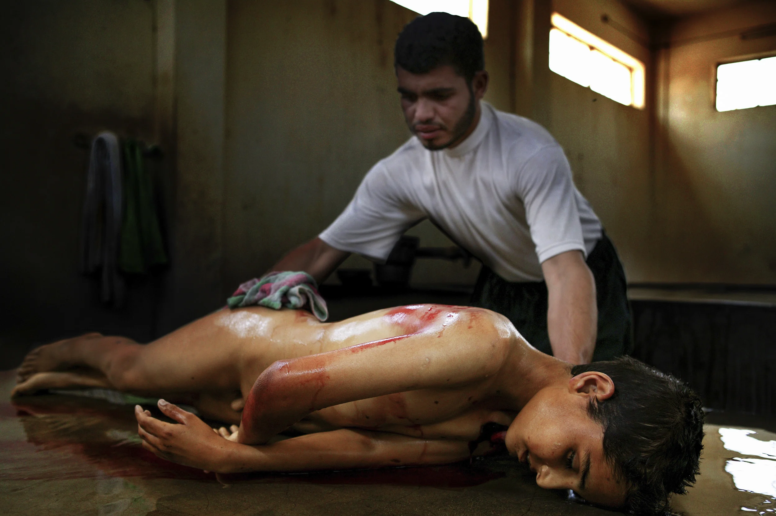 NAJAF, IRAQ-MAY 2005: Hussam Hassan washes the body of 12 year old Ali Basem Karim who was killed in Basra when the wedding he was attending was attacked by extremist militias. The wedding was attacked because they were celebrating and that was not considered apporopriate by the militia group. Another child was wounded in the attack. *** Local Caption *** Assignment Iraq