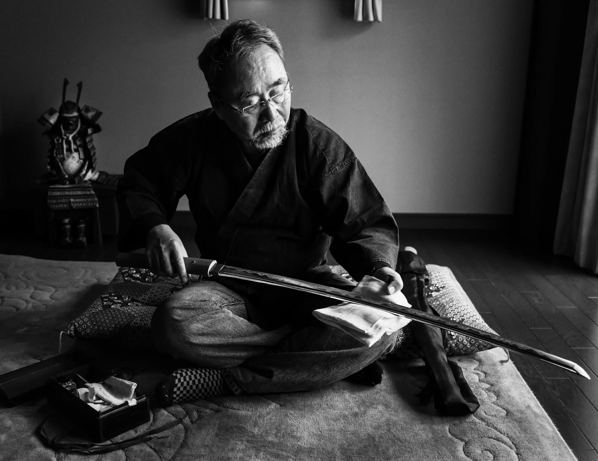 TOKYO, JAPAN, 22 OCTOBER 2014: Master Japanese swordsmith Yoshindo Yoshihara polishes a recently completed Katana sword in a room in his home in Tokyo, Japan. The Japanese sword is renowned for its excellence. There is a centuries old tradition of swordmaking in Japan, stretching back over a 1000 years. These days it remains a profession of very few craftsmen, with a even fewer master swordsmiths amongst them. The sword remains popular globally with those who can afford them. Prices can reach over 3 million Euros for an antique sword from a distinguished Samurai lineage.