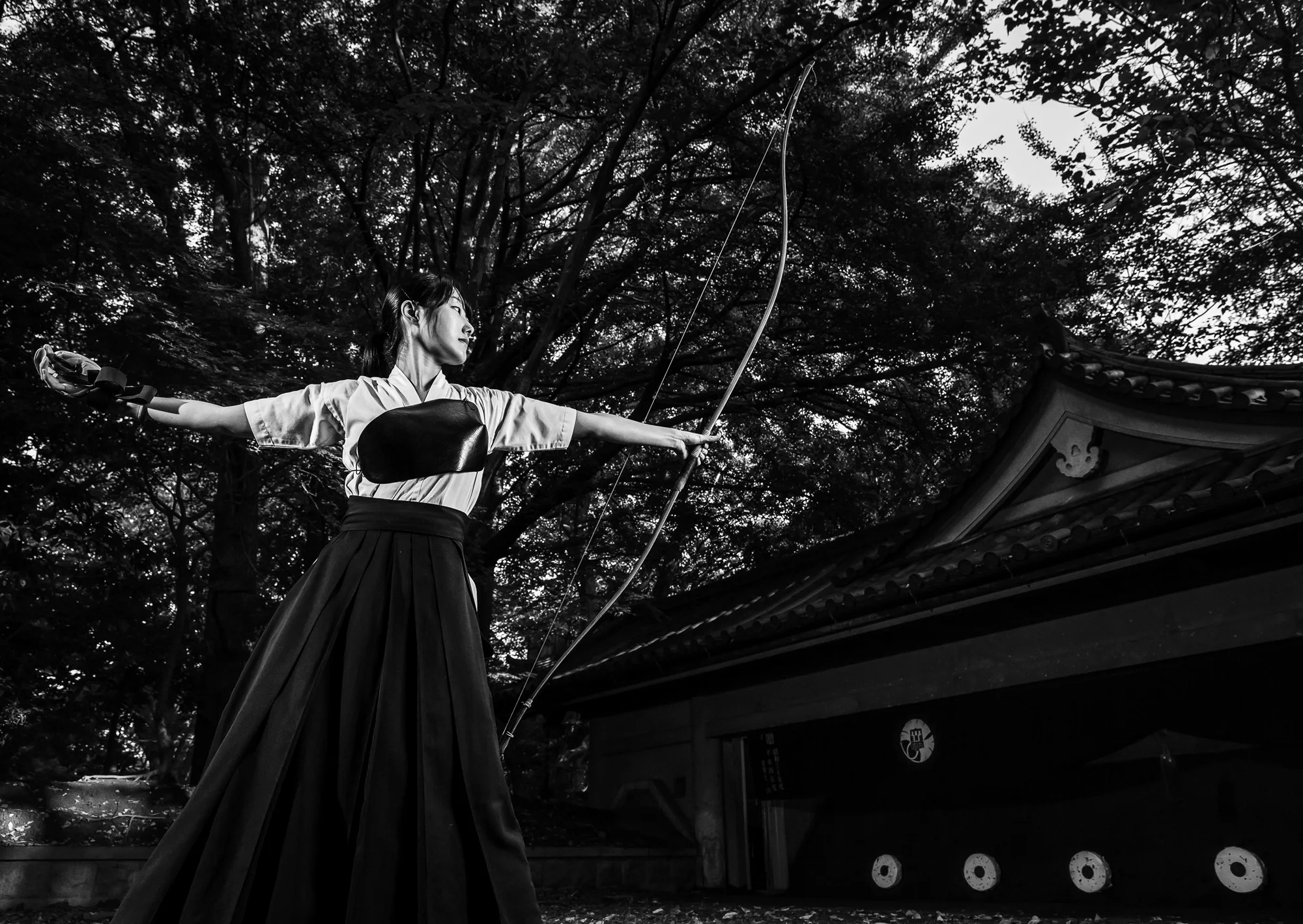TOKYO UNIVERSITY, TOKYO, JAPAN, 25 OCTOBER 2014: A female Kyudo archer holds her form after she releases her arrow at Tokyo University Kyudo dojo, Tokyo, Japan. Kyudo is seen by its practioners as more of a moving meditation than a sport of archery, with an emphasis on breath and perfection of movement. It is seen as one of the most static of the Bushido Samurai arts. All of the Samurai arts have aspects which stress these points of technique, artistry and flow.