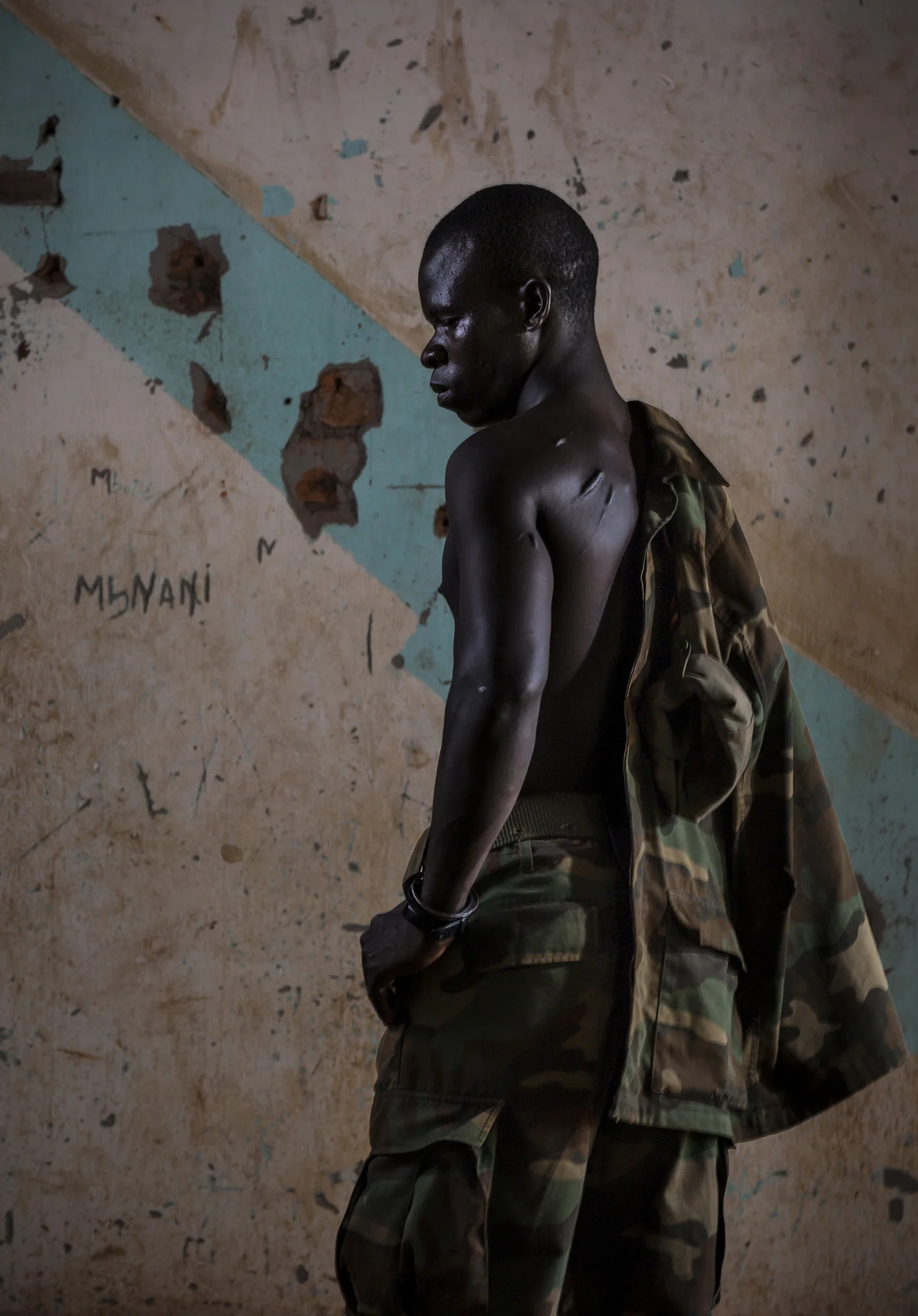 OBO, CENTRAL AFRICAN REPUBLIC, 18 NOVEMBER 2014: Recent Lord's Resistance Army defector, Michael Onen, photographed at the African Union Ugandan Army base at Obo, Central African Republic. Onen defected after spending 16 years in the LRA after being abducted as a child and taken far from his home village in the DR Congo. The scars on his back are as a result of beatings he received from his LRA captors. He defected on 11 September 2014 as he feared for his life after Joseph Kony, the leader of the LRA, disaproved of a relationship he has with a woman in the LRA. The Ugandan contingent as well as the Africom American personel based here are focused on the apprehension of the Lord's Resistance Army, the notorious rebel group led by Joseph Kony which has terrorized citizens of Uganda, C.A.R, South Sudan and the Democratic Republic of Congo for the last 4 decades. In recent times the LRA has turned its focus to Ivory as a means of income. This is having a devastating effect on elephant populations everywhere they operate. Michael Onen was part of the poaching team operating in Garamba National Park in the Democratic Republic of Congo. In 2012 this team killed 21 elephants, in 2014 they killed 26 elephants in Garamba. These tusks are currently in transit to Darfur, where the notorious leader of the LRA, Joseph Kony has ordered them to be brought. They will be carried by 3 separate groups for security, all moving in different directions. Michael Onen says that once in Darfur, these tusks will be sold to the Sudanese Army and transported to Khartoum from where they will make their way to China. Profits from the ivory will be used by the LRA for arms and resupply. Michael Onen was abducted by the LRA in 1998 while still a child, he was pressed into service by the terror group. He says that Kony lives by instilling fear in his fighters, resocializing children into killers who do his bidding. That bidding now includes the killing of elephants as well as people. (Photo by Bren