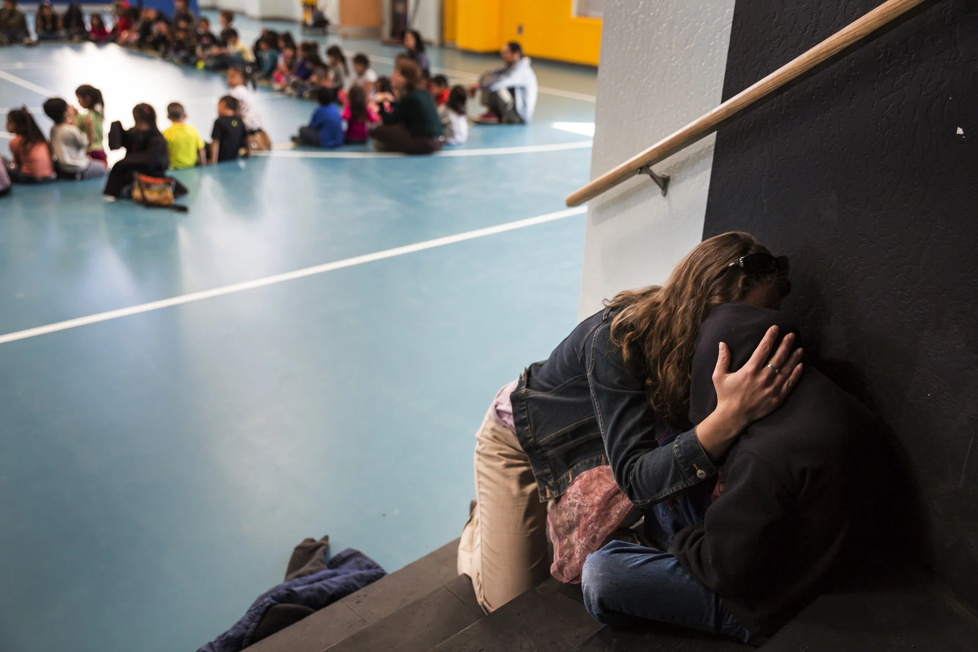 LEUPP, ARIZONA, 14 APRIL 2014: A teacher comforts an upset child as kids from the progressive Star charter school in Leupp Arizona attend an assembly on Monday at which all the children and staff shake hands with each other without exception. The Star school runs completely off the grid and has a Montessori style teaching schedule with a strong emphasis on Navajo Cultural values. The school has a very high success rate with its students with a 71% graduation rate compared to only 1% for Native pupils at Arizona state schools. Despite this, there is a movement to close Native schools in Arizona due to an unfair ratings system which does not take into account reservation issues and Navajo based teaching techniques. (Photo by Brent Stirton/Reportage for Le Figaro.)