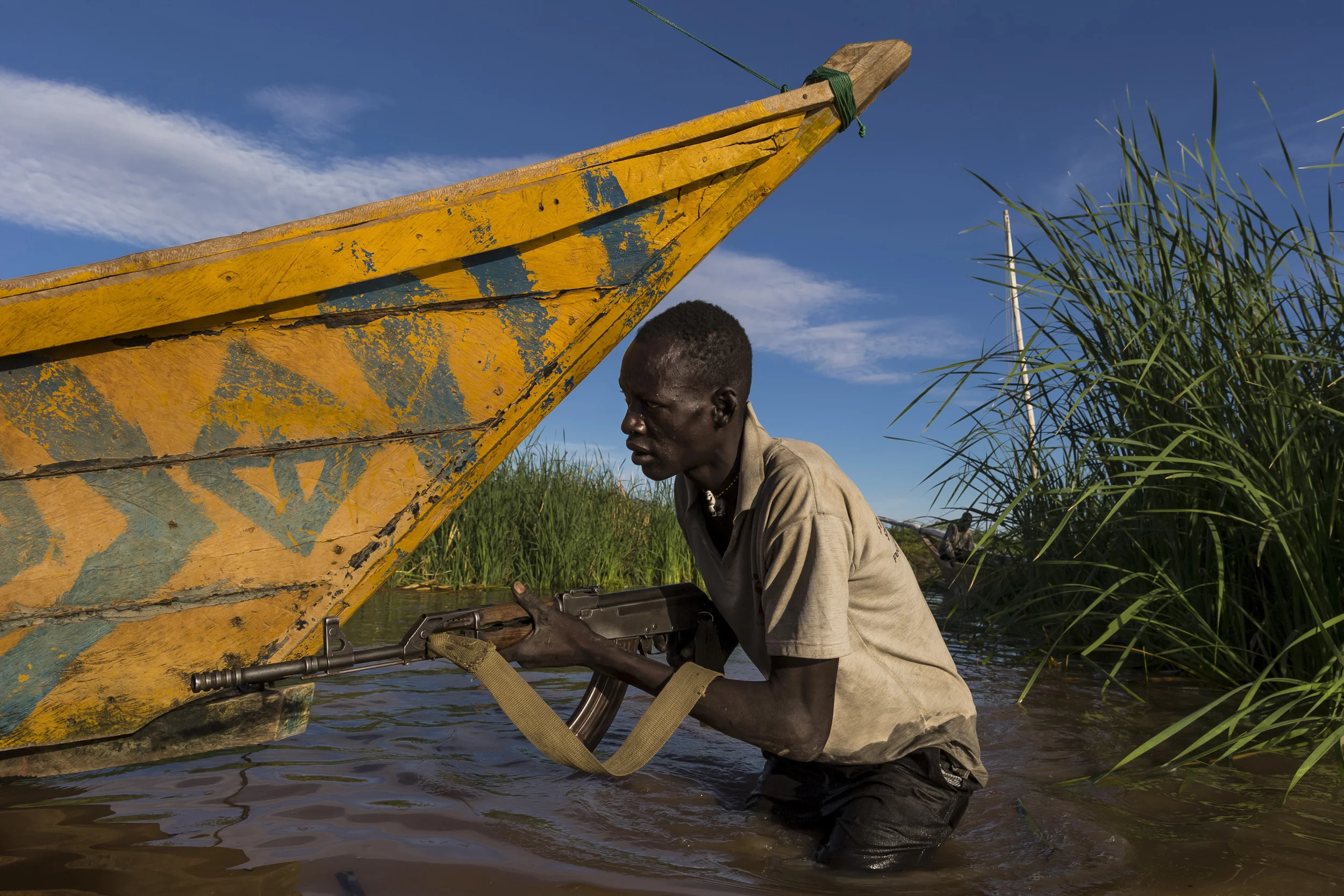 LOWARENGAK, TURKANA, KENYA, 10 OCTOBER 2014: Village defence man Steven Lajore, 27, is from an internally displaced Turkana community who have been moved off their land by Dassanech tribesman who raided their cattle and killed their people, Turkana, Kenya. These Turkana now practise fishing as opposed to their traditional pastoralism as their main means of subsistence. Steven is seen guarding the boats from Dassanech raids. The Dassenech have in fact come illegally over the Ethiopian border into Turkana land. They were pressured by sugar cane farms on the lower Omo river which is the main tributary for Lake Turkana, the largest desert lake in the world. These sugar cane farms robbed the Dassenech of tradional grazing land and water rights and so they moved over the border into Turkana territory and ongoing conflict is the result. This pattern is likely to increase as Ethiopia's Gibe 3 dam comes online next year. This will reduce the flow of the Omo river to one fifth of its current size. This will decimate the fertile flood plain in the region and the tribesmen along the Omo will fight for diminishing resources as a result. This conflict will be likely to continue in Kenya's Turkana region as all around the lake hundreds of thousands of tribespeople will find themselves competing for less and grazing, fishing and clean water sources. A series of droughts have reduced most of these pastoralists to fishing as their chief source of subsistence due to huge cattle and goat deaths. The massively reduced flow of the Omo, source of 90% of Lake Turkana's water, could have a devastating effect on this food and income source. The Ethiopian government has conducted no Environmental Impact Assessment for their dams and has yet to respond to these issues. (Photo by Brent Stirton/Reportage by Getty Images for HRW.)