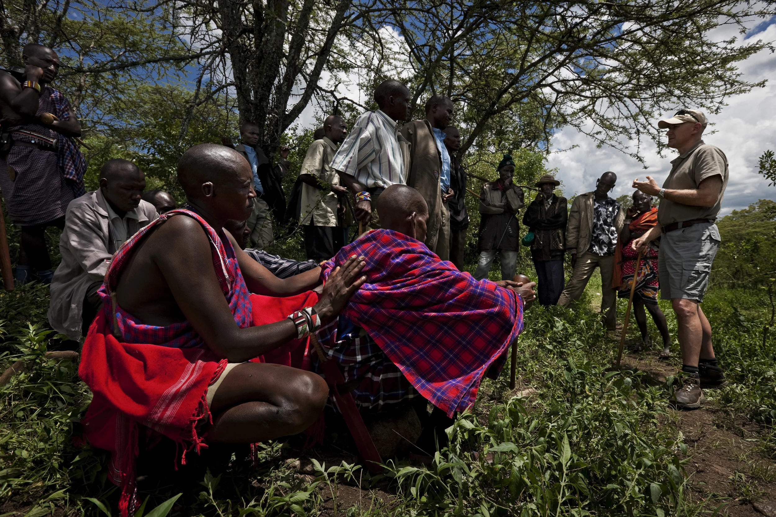 OLDEREKESI RANCH, MASAAI MARA, FEBRUARY 2010: An age group of Olderekesi community elected Masaai elders discuss the pros and cons of turning away for cattle pastoralism towards wildlife conservation as a primary income source, Olderekesi Ranch, Masaai Mara, Kenya, 19 February 2010. This group is meeting with Calvin Cottar, a white Kenyan who is attempting to deal with the Masaai on this land where he has a safari camp in which he wants to be involved with the local Masaai. If the land is privatised and the Masaai decide to go the wildlife conservation route they will make a guaranteed income from it through Calvin Cottar and other Safari camps on the leased Masaai land. The pastoralists across Kenya have found themselves at a tipping point, lack of land, overpopulation, pastoralist conflicts, the worst drought in over 100 years and huge subsequent cattle losses have driven the pastoralist tribes of Kenya to a point where change is becoming inevitable. The Masaai Mara has experienced tremendous exploitation by different tourist facilities which are not licensed and standardised. As a result there are too many illegal and unregulated lodges and this is having a drastic effect on the unique wildlife of Kenya as well on the pastoralists who no longer have enough land to maintain their nomadic cattle based lifestyle. (Photo by Brent Stirton/Reportage by Getty Images.)