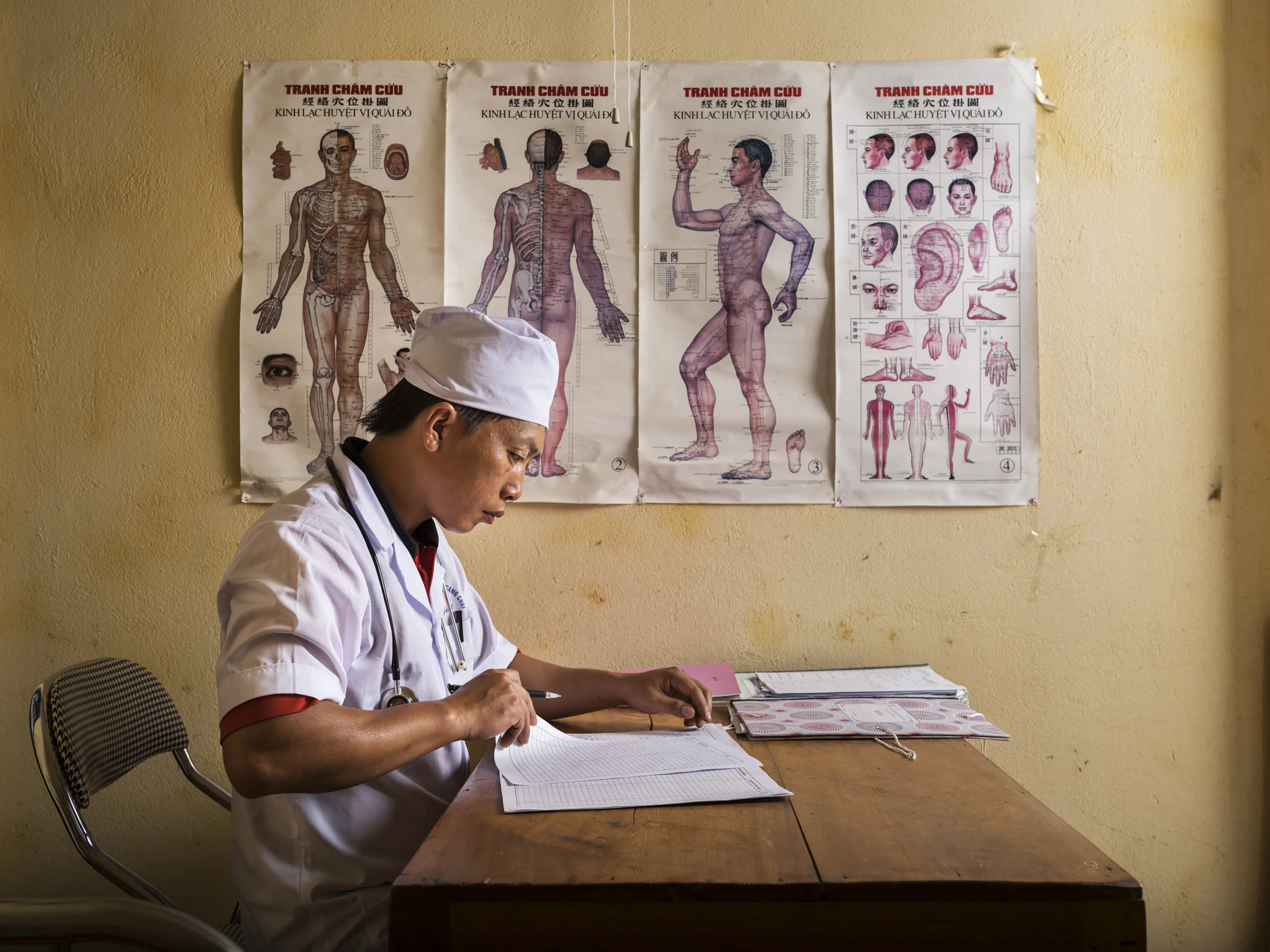 MU CANG CHAI, YEN BAI, VIETNAM, 6 JUNE 2015: Dr Chang As Sinh, 37, updates his records in his office in the community hospital in the hills over Mu Cang Chai. Sinh has worked in this community for over 10 years and is the only doctor in the community. He speaks the local Hmong dialect and is instrumental in medical care delivery to this remote ethnic minority. (Photo by Brent Stirton/Novartis)