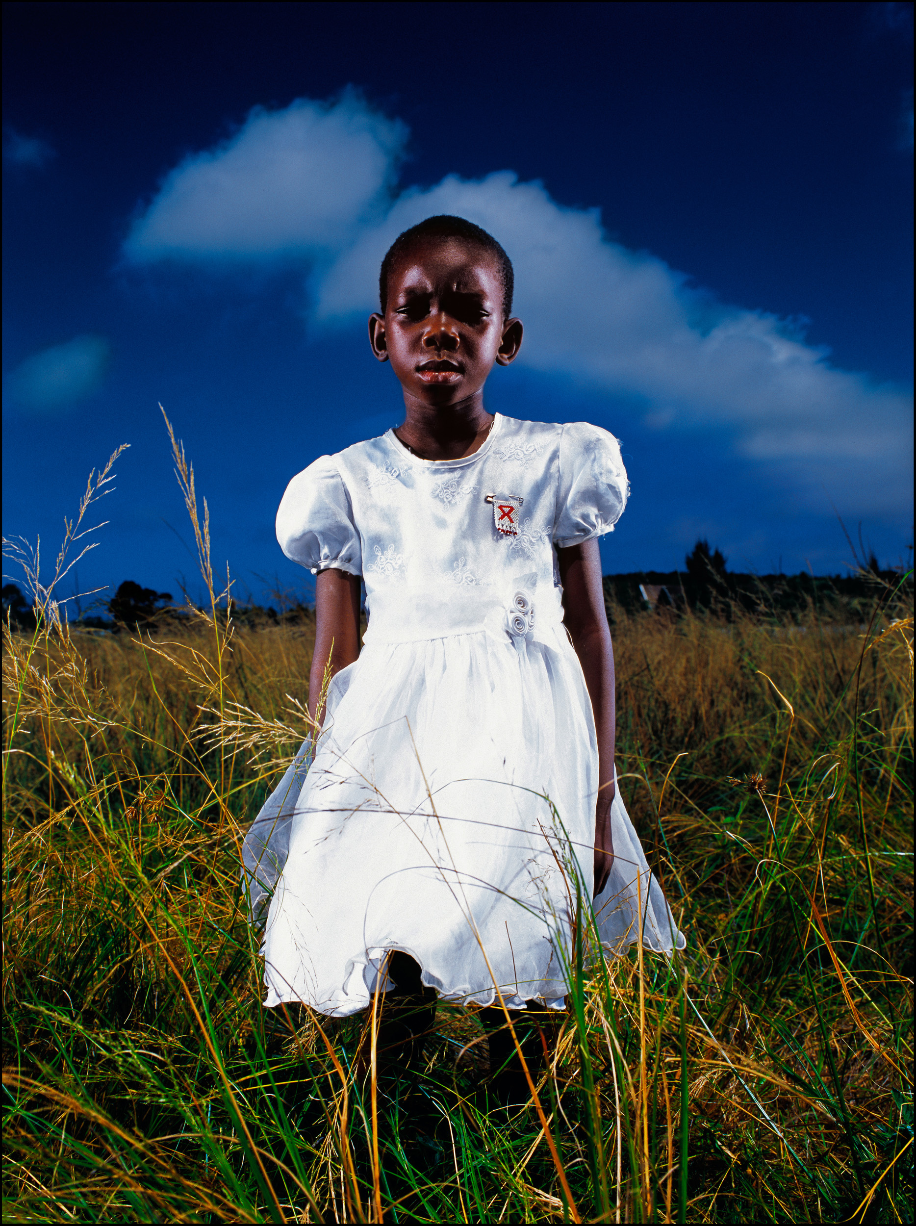 RICHARDS BAY, SOUTH AFRICA-MAY 2004: A young aids orphan stands alone in a field after a church service. PHOTO BY BRENT STIRTON/GETTY IMAGES.