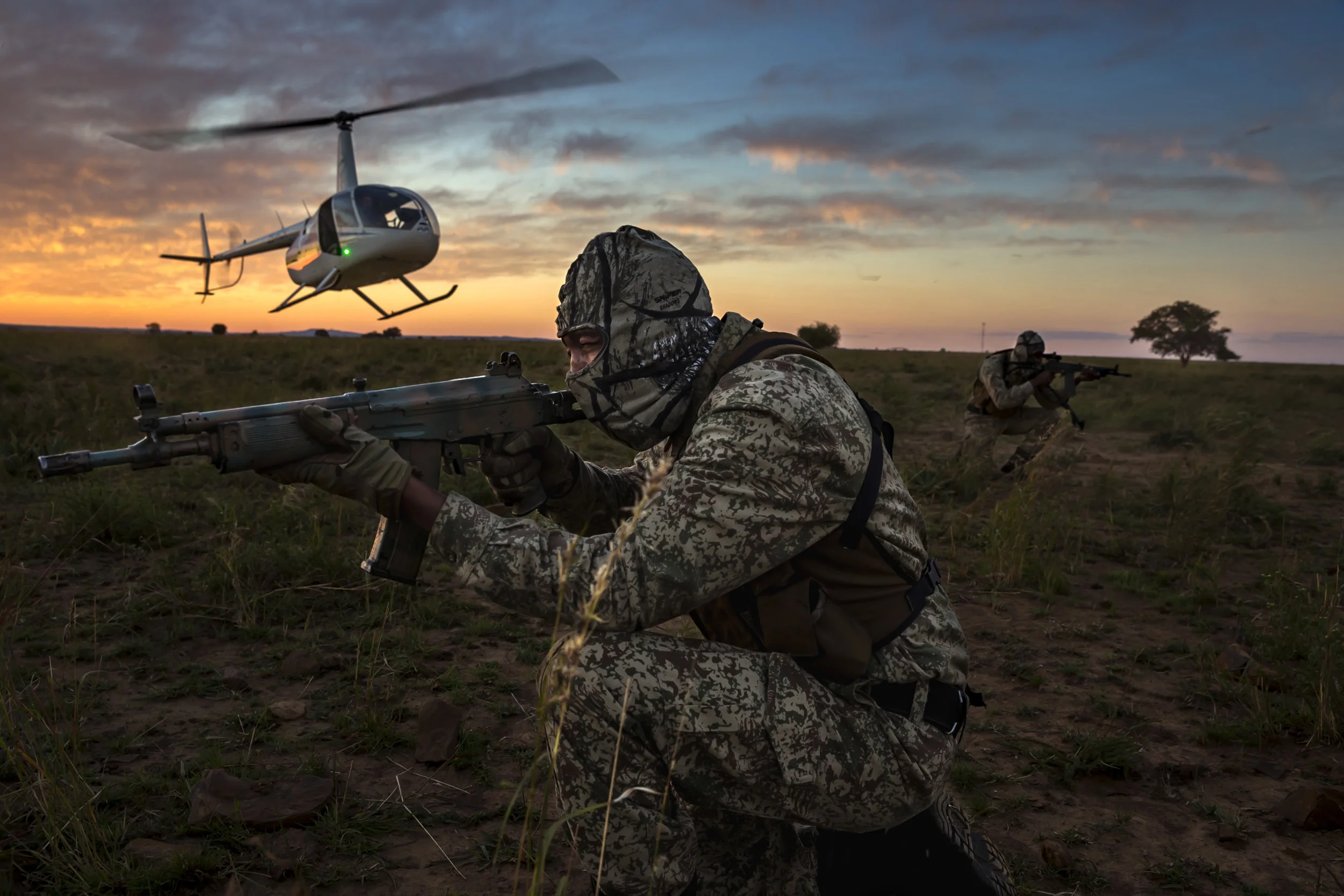 BUFFALO DREAM RANCH, KLERKSDORP, SOUTH AFRICA, 24 MAY 2016: A two-man security team deploys by helicopter at sunset for anti-poaching duties on the worlds largest Rhino breeding ranch. The teams are at work 24 hours a day and conduct security operations from rotating positions, observation points and on mobile patrols on foot, in vehicles and by helicopter. John Hume has close to 1400 Rhino to protect on his property and they are constantly monitored by his vet Dr Michelle Otto and by Hume’s Security teams. Hume’s running costs are close to 5 million Rand a month, around $330, 000.00 per month. $200,000.00 of that is spent on security. Hume is a long time proponent of legalizing the Rhino horn trade by using humane dehorning and is one of the biggest influences in trying to get CITES to change their anti-trade stance. Hume is reputed to have more than 5 tons of rhino horn in secure locations. This would be worth around $40, 000, 000.00 on the Asian market at current prices. There are many supporters of the pro-trade agreement, with more than 1300 rhino likely to be poached per annum in this current crisis. Critics of trade state that legalizing horn trade would create loopholes that would exacerbate the killing of rhino. (Photo by Brent Stirton/Reportage by Getty Images for National Geographic Magazine.)