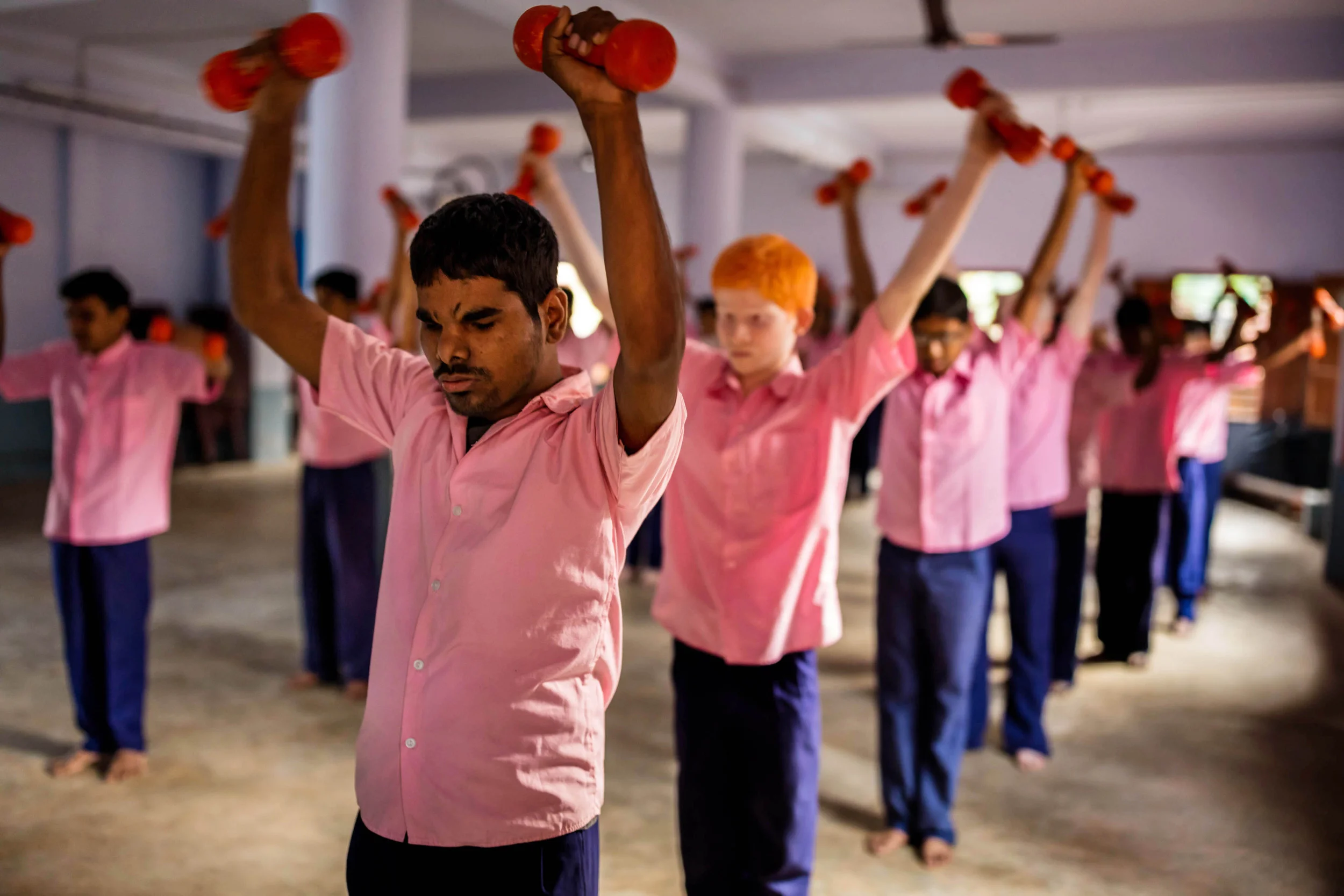 VIVEKANANDA MISSION ASRAM, HALDIA, WEST BENGAL, INDIA, JANUARY 16, 2016: Blind male students of the Vivekananda Mission Asram school for the blind are seen at their calisthenics and yoga class in the main assembly hall. Vivekananda has had a number of paraolympic athletes. This is the highest rated school for blind children in India, the country with the highest number of blind people, arond 1% of their population, approximately 12 million people. Vivekanda Mission Asram provides care to some of the poorest of blind children, providing them with an education and tools for life survival once they leave the Asram after graduating. The children learn a normal school curiculum through braile and a team of dedicated teachers. Vocationa training is also available at the Asram in weaving, candle making amongst other skills that can add meaning to a blind life in India. Most of the blind in India end up as beggars, this school offers students a chance to be more than that. A number of their students have gone on to become senior teachers for sighted pupils, lawyers and business people. In these images the boys and girls are seen attending school lessons, learning Braille, music as well as scenes from their hostel residence and sports activities. (Photo by Brent Stirton/Reportage for National Geographic Magazine.)