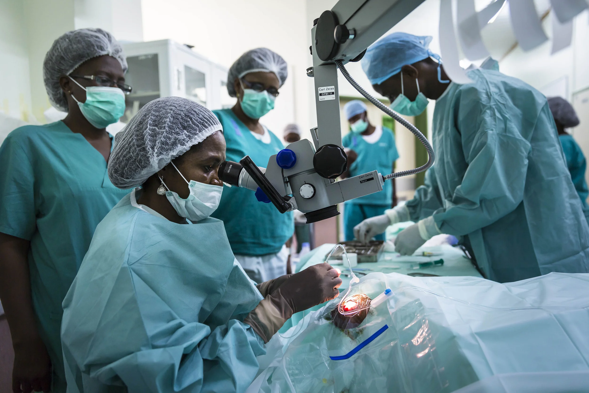 OMARURU, NAMIBIA, 2 November 2015: Dr Helena Ndume, winner of the Mandela prize and Namibia's most celebrated opthmalogist, performs cataract surgery on patients attending a blindness clinic in Omaruru, Namibia. Most of these people will recover a degree of sight that has been lost to them for a few years and they are grateful for the opportunity to see again.
These camps are held all over Namibia and subsidized by a mix of government funding and donor equipment. They tend to cater to sections of the population that do not receive regular eye care, mostly as a result of poverty. The applicants are screened and if the diagnosis is a mature cataract, they are selected as candidates for a simple operation which in fifteen minutes lends signicant sight to their world. The cataract is removed by a surgical vacuum and a new lens in inserted. Bandages are removed the next day and in most cases a real improvement in vision is the result. (Photo by Brent Stirton/Reportage for National Geographic Magazine.)