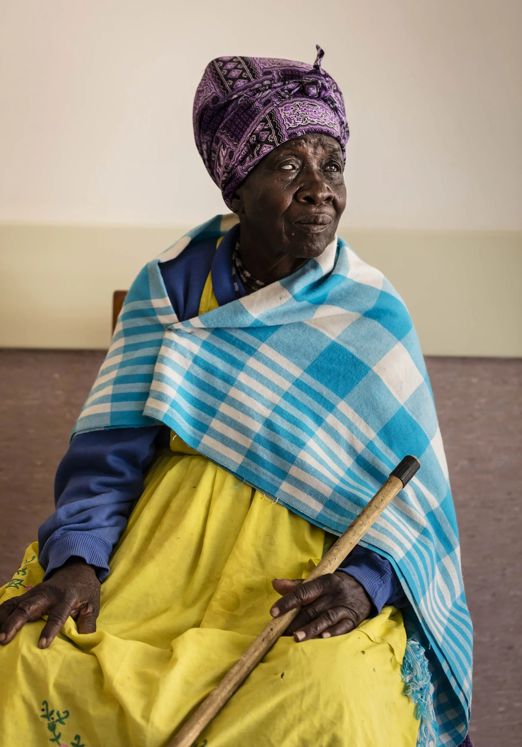 OMARURU, NAMIBIA, 1 NOVEMBER 2015: A blind Damara Nama woman, Theresa Tsamasas, 85, is seen waiting to be screened after arriving from Okombei, a location over 100 kilometers away, at Omaruru District Hospital, Namibia. Theresa lost one eye to a stick when she was a child and now fears for her future as she has lost her only sighted eye to a mature cataract.
These camps are held all over Namibia and cater to sections of the population that do not receive regular eye care, mostly as a result of poverty. They are often the result of donor efforts to make the surgery and lenses possible for impoverished communities. The applicant are screened and if the diagnosis is a mature cataract, they are selected as candidates for a simple operation which in fifteen minutes lends signicant sight to their world. The cataract is removed by a surgical vacuum and a new lens in inserted. Bandages are removed the next day and in most cases a real improvement in vision is the result. (Photo by Brent Stirton/Reportage for National Geographic Magazine.)