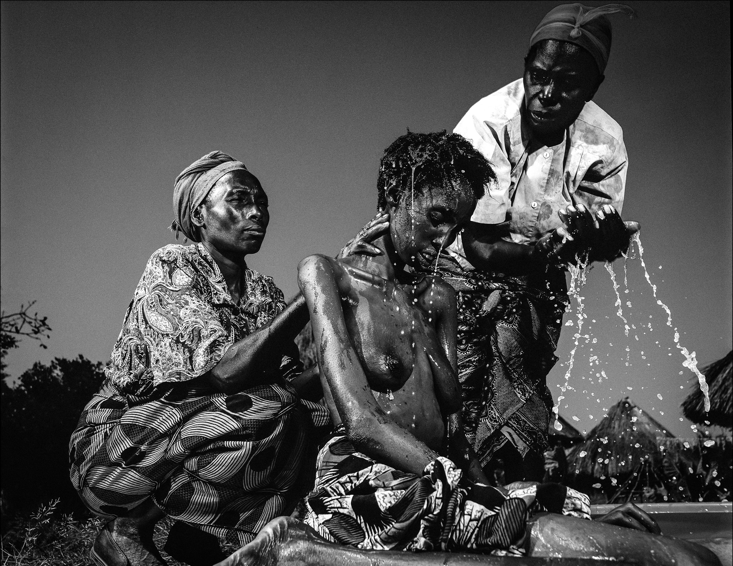 CHINGOLA, NORTHERN ZAMBIA, FEBRUARY 2002: A dying 17 year girl old succumbs to full-blown AIDS as her mother and aunt bathe her for the last time, rural Chingola, North Zambia, 8 February 2002. A lack of access to clean drinking water accelerates th