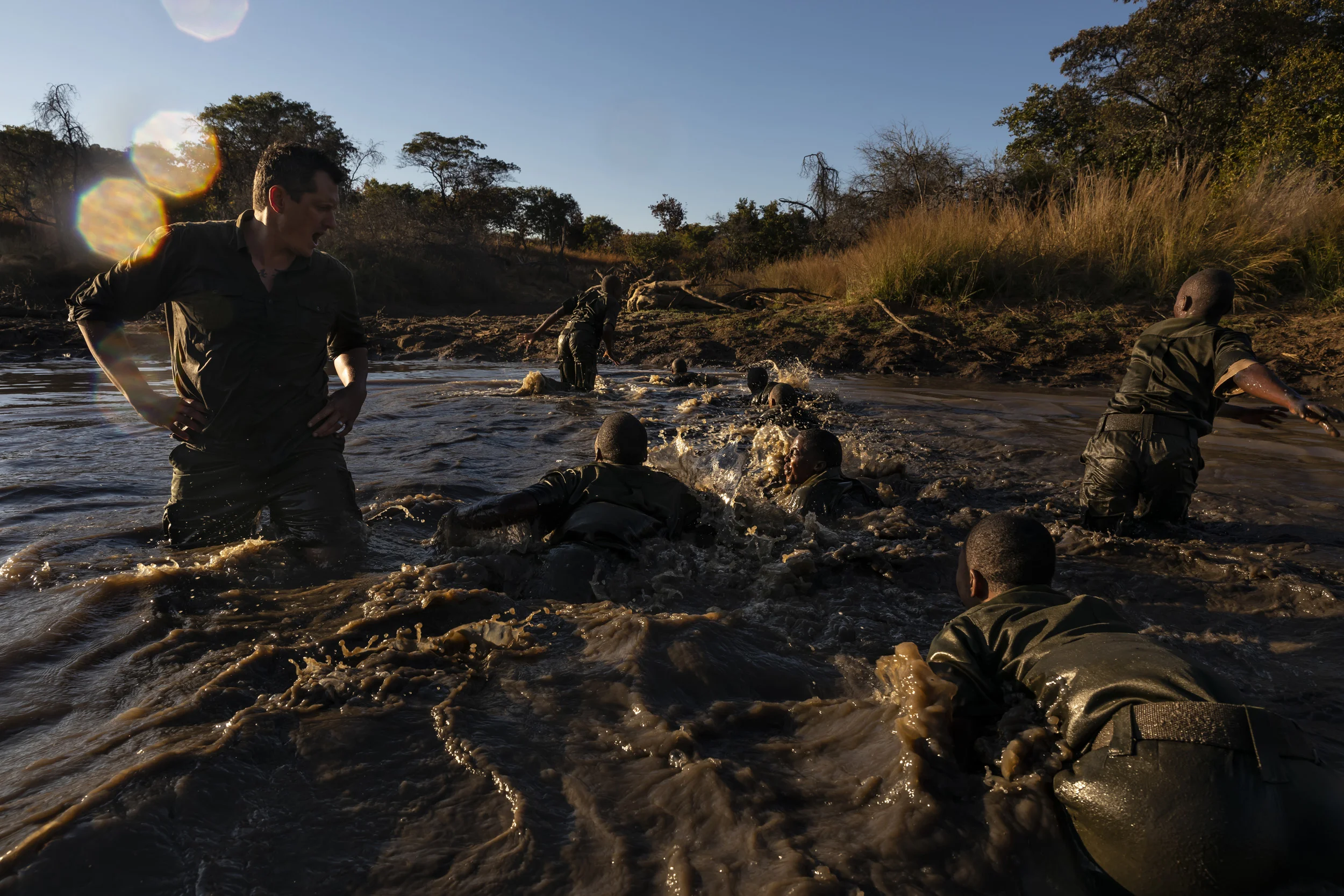 PHUNDUNDU WILDLIFE AREA, ZIMBABWE, JUNE 2018: Members of the all female conservation ranger force known as Akashinga undergo tough training in the bush near their base. Akashinga (meaning the ‘Brave Ones’ in local dialect) is a community-driven conservation model, empowering disadvantaged women to restore and manage a network of wilderness areas as an alternative to trophy hunting. Many current western-conceived solutions to conserve wilderness areas struggle to gain traction across the African continent. Predominately male forces are hampered by ongoing corruption, nepotism, drunkenness, aggressiveness towards local communities and a sense of entitlement. The I.A.P.F, the International Anti-Poaching Foundation led by former Australian Special Forces soldier Damien Mander, was created as a direct action conservation organisation to be used as a surgical instrument in targeting wildlife crime. In 2017 they decided to innovate, using an all- female team to manage an entire nature reserve in Zimbabwe. The program builds an alternative approach to the militarized paradigm of ‘fortress conservation’ which defends colonial boundaries between nature and humans. While still trained to deal with any situation they may face, the team has a community-driven interpersonal focus, working with rather than against the local population for the long-term benefits of their own communities and nature. Cut off from places of worship and burial, grazing areas, access to water, food, traditional medicine and given limited opportunity for employment or tourism benefits, it’s little wonder many of these communities struggle to see any value in conservation efforts.
Women have traditionally played major roles in battle and are now re-emerging as key solutions in law enforcement and conflict resolution. In the Middle-East, counterinsurgency operations that involve penetrating and working with the local population to try and win the hearts and minds have become fundamentally relian