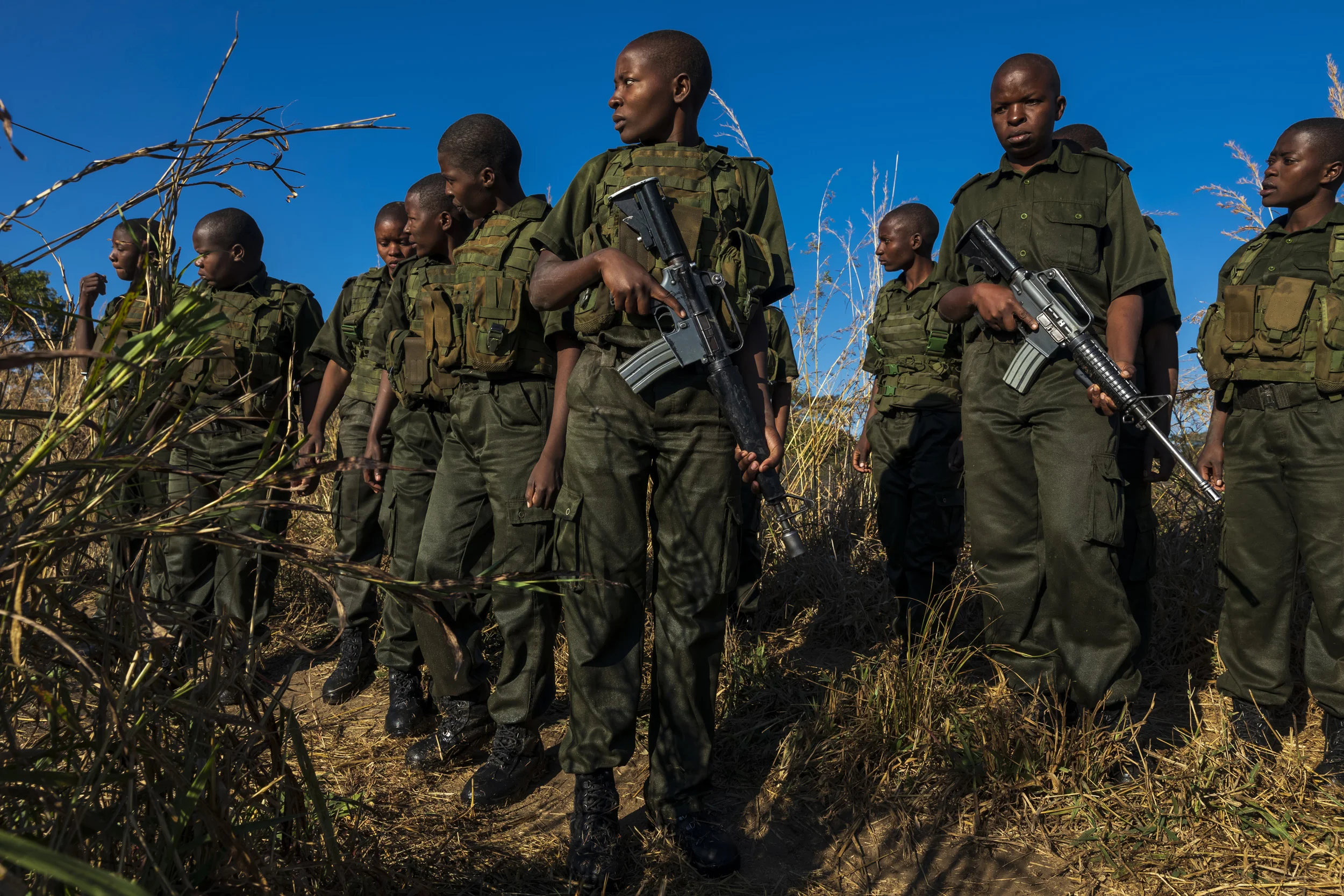 PHUNDUNDU WILDLIFE AREA, ZIMBABWE, JUNE 2018: Members of the all female conservation ranger force known as Akashinga undergo tough training in the bush near their base. Akashinga (meaning the ‘Brave Ones’ in local dialect) is a community-driven conservation model, empowering disadvantaged women to restore and manage a network of wilderness areas as an alternative to trophy hunting. Many current western-conceived solutions to conserve wilderness areas struggle to gain traction across the African continent. Predominately male forces are hampered by ongoing corruption, nepotism, drunkenness, aggressiveness towards local communities and a sense of entitlement. The I.A.P.F, the International Anti-Poaching Foundation led by former Australian Special Forces soldier Damien Mander, was created as a direct action conservation organisation to be used as a surgical instrument in targeting wildlife crime. In 2017 they decided to innovate, using an all- female team to manage an entire nature reserve in Zimbabwe. The program builds an alternative approach to the militarized paradigm of ‘fortress conservation’ which defends colonial boundaries between nature and humans. While still trained to deal with any situation they may face, the team has a community-driven interpersonal focus, working with rather than against the local population for the long-term benefits of their own communities and nature. Cut off from places of worship and burial, grazing areas, access to water, food, traditional medicine and given limited opportunity for employment or tourism benefits, it’s little wonder many of these communities struggle to see any value in conservation efforts.
Women have traditionally played major roles in battle and are now re-emerging as key solutions in law enforcement and conflict resolution. In the Middle-East, counterinsurgency operations that involve penetrating and working with the local population to try and win the hearts and minds have become fundamentally relian