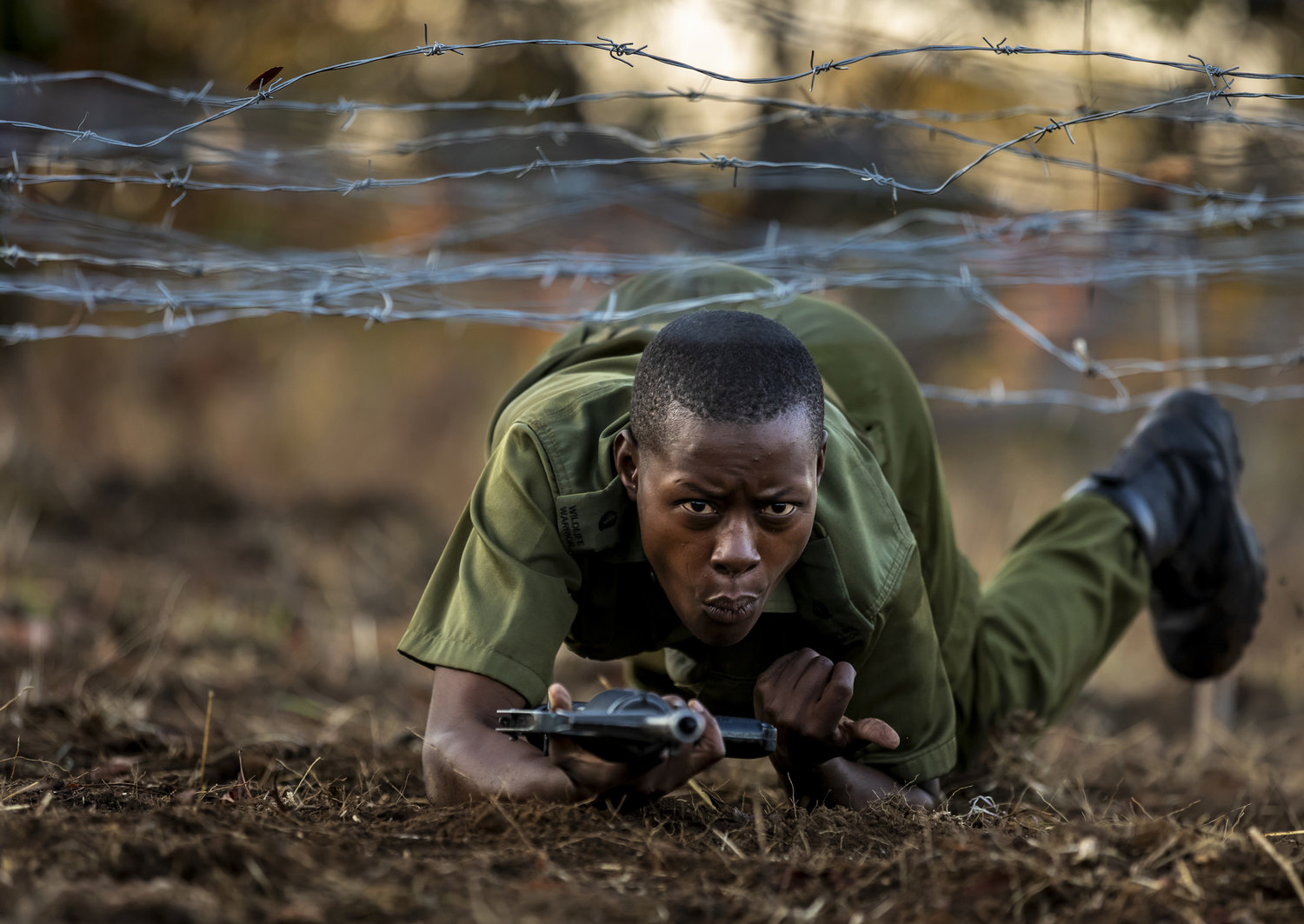  PHUNDUNDU WILDLIFE AREA, ZIMBABWE, JUNE 2018: Members of the all female conservation ranger force known as Akashinga undergo tough training in the bush near their base. Akashinga (meaning the ‘Brave Ones’ in local dialect) is a community-driven conservation model, empowering disadvantaged women to restore and manage a network of wilderness areas as an alternative to trophy hunting. Many current western-conceived solutions to conserve wilderness areas struggle to gain traction across the African continent. Predominately male forces are hampered by ongoing corruption, nepotism, drunkenness, aggressiveness towards local communities and a sense of entitlement. The I.A.P.F, the International Anti-Poaching Foundation led by former Australian Special Forces soldier Damien Mander, was created as a direct action conservation organisation to be used as a surgical instrument in targeting wildlife crime. In 2017 they decided to innovate, using an all- female team to manage an entire nature reserve in Zimbabwe. The program builds an alternative approach to the militarized paradigm of ‘fortress conservation’ which defends colonial boundaries between nature and humans. While still trained to deal with any situation they may face, the team has a community-driven interpersonal focus, working with rather than against the local population for the long-term benefits of their own communities and nature. Cut off from places of worship and burial, grazing areas, access to water, food, traditional medicine and given limited opportunity for employment or tourism benefits, it’s little wonder many of these communities struggle to see any value in conservation efforts. 
Women have traditionally played major roles in battle and are now re-emerging as key solutions in law enforcement and conflict resolution. In the Middle-East, counterinsurgency operations that involve penetrating and working with the local population to try and win the hearts and minds have become fundamentally relian 
