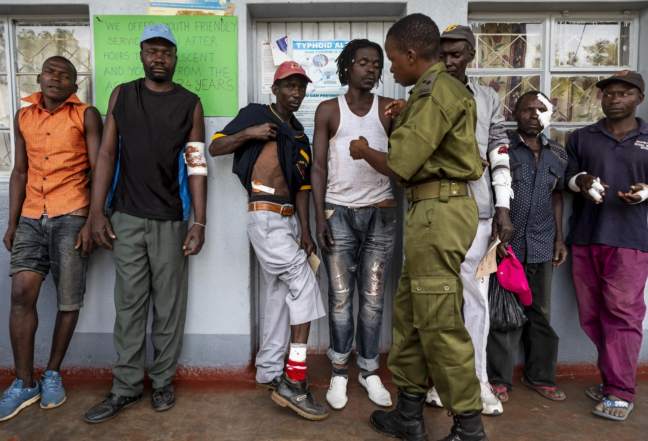 KAROI, ZIMBABWE, DECEMBER 2018: Seven village men injured by a leopard receive treatment from Akashinga Sergeant Vimbai Kumire. The men were injured when they foolishly pursued and killed a leopard that had strayed into their fields. Although this is an illegal act, the Akashinga forces deployed to help the injured and take the more seriously wounded to hospital over 50km away. This is the kind of community relations these women rely on to be effective in their work. Akashinga (meaning the ‘Brave Ones’) is a community-driven conservation model, empowering disadvantaged women to restore and manage a network of wilderness areas as an alternative to trophy hunting in Zimbabwe.