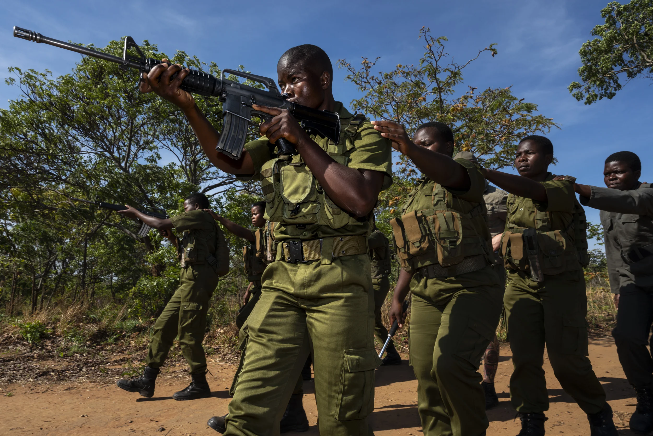 PHUNDUNDU WILDLIFE AREA, ZIMBABWE, DECEMBER 2018: Members of the all female conservation ranger force known as “Akashinga” undergo house penetration training near their base for operations against organized environmental criminals. Akashinga (meaning the ‘Brave Ones’) is a community-driven conservation model, empowering disadvantaged women to restore and manage a network of wilderness areas as an alternative to trophy hunting in Zimbabwe. Predominately male forces are often hampered by ongoing corruption, nepotism, drunkenness, aggressiveness towards local communities and a sense of entitlement. The International Anti-Poaching Foundation, led by former Australian Special Forces soldier Damien Mander, was created as a direct action conservation organization used as a surgical instrument in targeting wildlife crime. In 2017 they decided to innovate, using an all- female team to manage an entire nature reserve in Zimbabwe. The program builds an alternative approach to the militarized paradigm of ‘fortress conservation’ that defends colonial boundaries between nature and humans. While still trained to deal with any situation they may face, the team has a community-driven interpersonal focus, working with rather than against the local population for the long-term benefits of their own communities and nature.