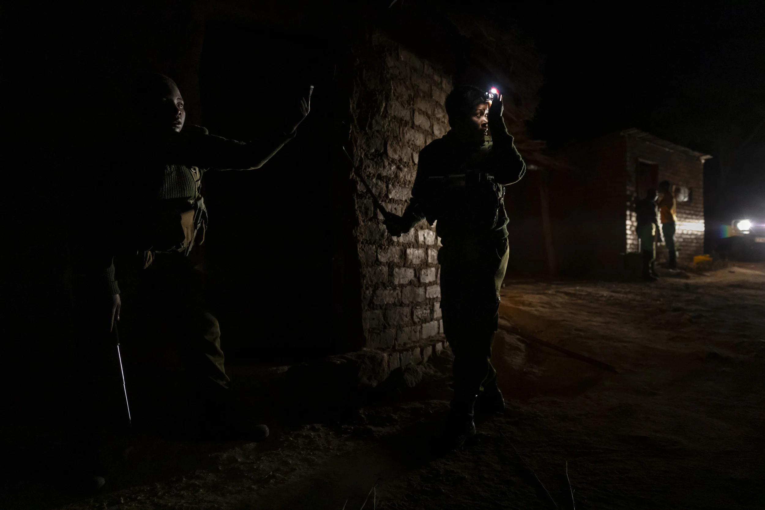 KAROI, ZIMBABWE, DECEMBER 2018: Members of the all- female conservation ranger force known as “Akashinga” prepare to enter a dwelling during a 2am night operation against a known poaching group, working alongside Zimbabwean Criminal Investigation Division officers. Intelligence for the operation was gathered through the Akashinga community intelligence networks and MAPP, an anti-poaching group that works hand in hand with these female rangers. Akashinga (meaning the ‘Brave Ones’ in local dialect) is a community-driven conservation model, empowering disadvantaged women to restore and manage a network of wilderness areas as an alternative to trophy hunting in Zimbabwe. Predominately male forces are hampered by ongoing corruption, nepotism, drunkenness, aggressiveness towards local communities and a sense of entitlement. The I.A.P.F, the International Anti-Poaching Foundation led by former Australian Special Forces soldier Damien Mander, was created as a direct action conservation organisation to be used as a surgical instrument in targeting wildlife crime. In 2017 they decided to innovate, using an all- female team to manage an entire nature reserve in Zimbabwe. The program builds an alternative approach to the militarized paradigm of ‘fortress conservation’ which defends colonial boundaries between nature and humans. While still trained to deal with any situation they may face, the team has a community-driven interpersonal focus, working with rather than against the local population for the long-term benefits of their own communities and nature.