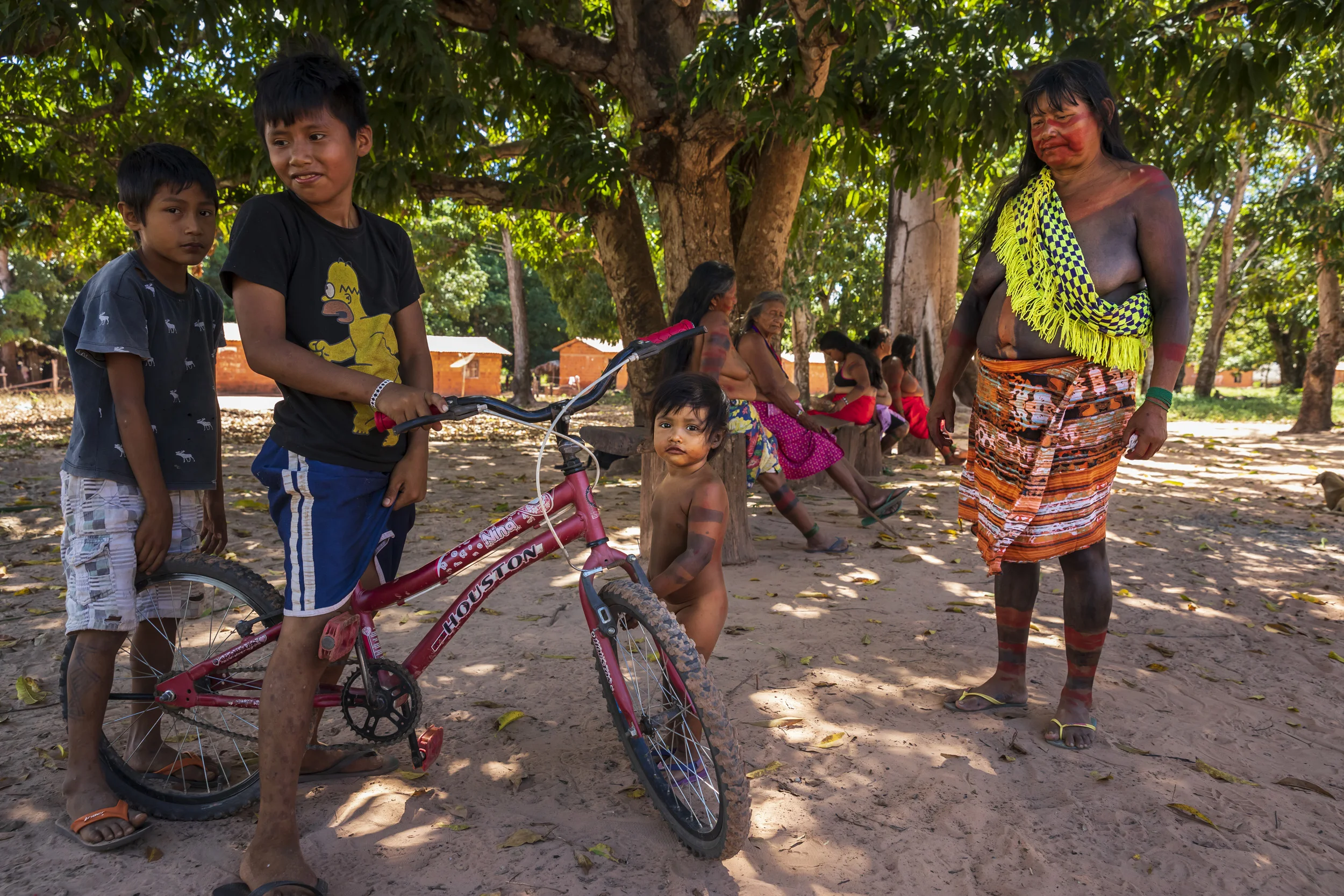 MARANHAO, BRAZIL, JUNE 2018: Indigenous people from the village of Governador prepare for a dance in the central village in the tribal area for Gaviao Indigenous people. TI Governador is the ancestral territory of the Gavião people; it encompasses 42,000 hectares of Amazon forest. Governador has been noticeably affected by deforestation, with whole areas razed of trees, dry riverbeds and frequent forest fires. People in this village say that the old days were better, their forests held more animals for hunting, more fruit and there were no problems with loggers illegally cutting their timber.
This village was running a regular forest guardian patrol but funding for indigenous NGO’s has dried up and at this time there are no patrols due to that lack of funding. 3 years ago this village confiscated logging vehicles by force which led to a confrontation with the loggers. The village was abandoned by the military police, who were supposed to protect them from the illegal loggers. The military police only returned a week later during which time the village had to defend themselves. Environmental defenders in Governador have been subjected to threats, death threats, intimidation, assault and armed attacks. Defenders reported receiving threatening anonymous calls usually after seizing a truck during one of the patrols; sometimes the callers would also issue death threats towards the defender or towards their whole village. Loggers residing in the neighboring town have intimidated and physically assaulted at least 2 indigenous leaders when they traveled to town. In one instance loggers intimidated shop owners in town so they wouldn’t sell gas to indigenous people for two weeks. To date, there seem to have been no killings of Gavião environmental defenders in retaliation for their activism.
Gavião people are ambivalent about the role of the State. Several environmental defenders have worked or continue to work with Funai, the specialised governmental agency for indig