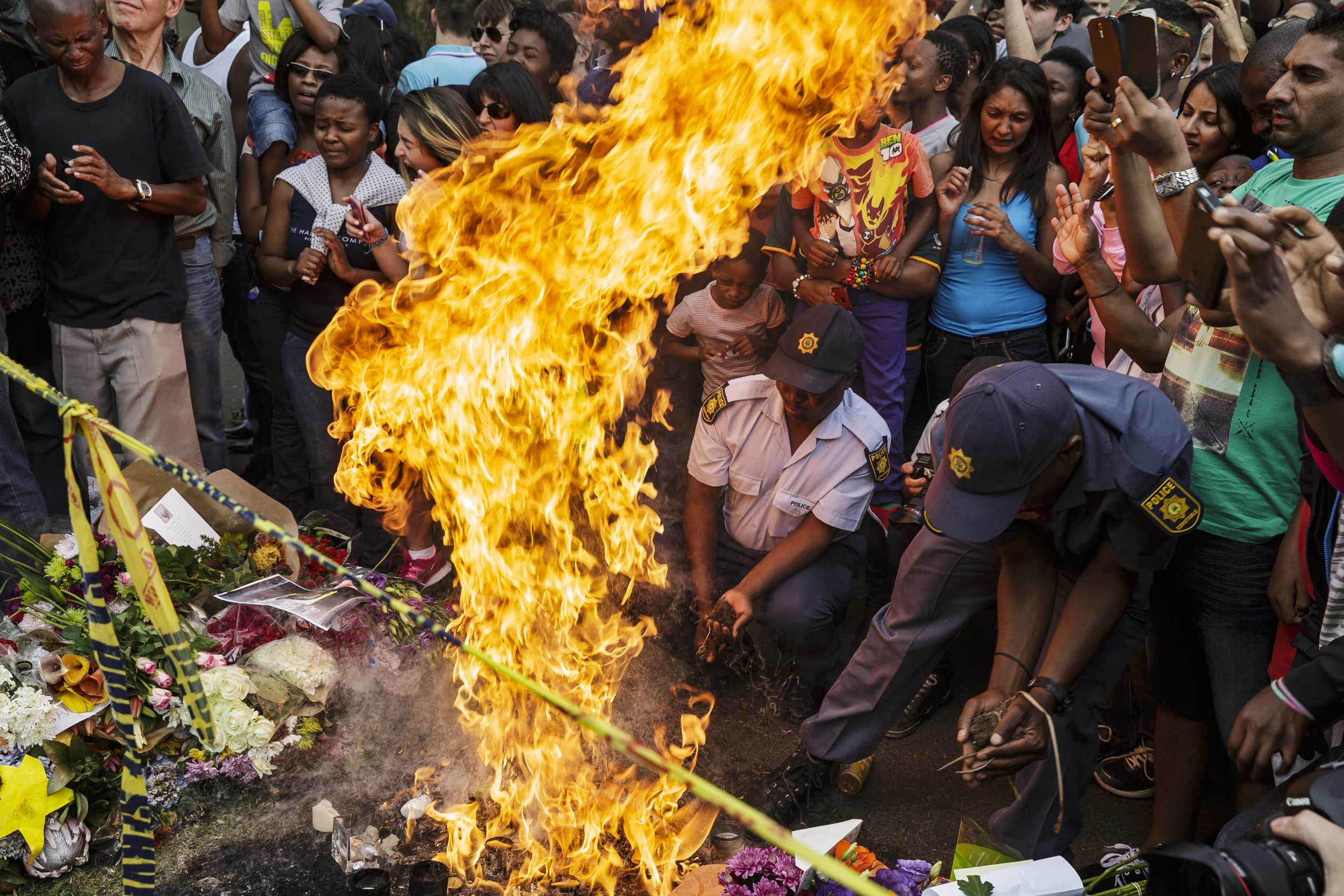 HOUGHTON, JOHANNESBURG, SOUTH AFRICA, 7 DECEMBER 2013: A fire in a shrine to Nelson Mandela veers briefly out of control outside of Nelson Mandela's Johannesburg home as crowds of people come to pay tribute to the icon of South Africa democracy, 7 December 2013. (Photo by Brent Stirton/Reportage by Getty Images.)