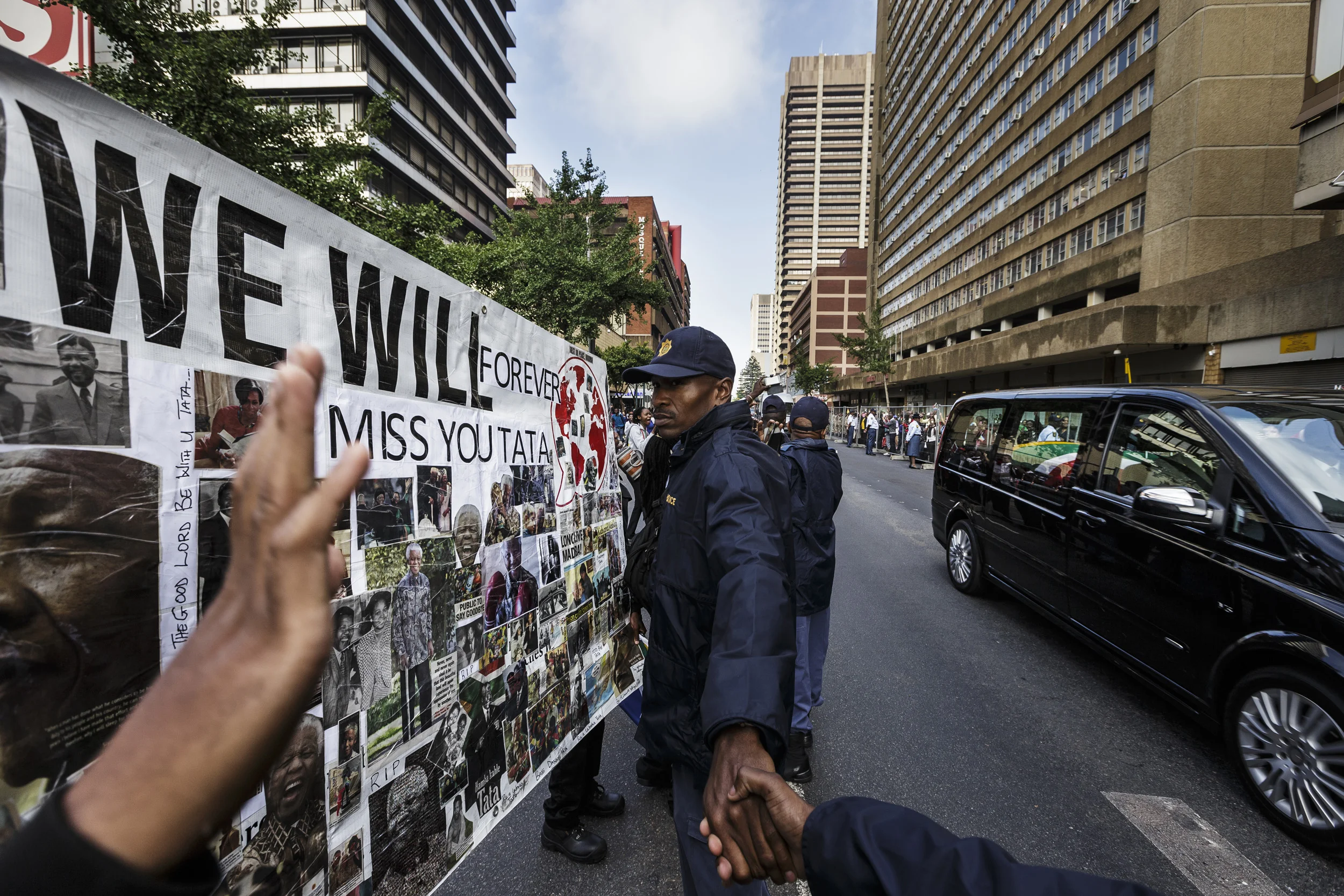 PRETORIA, SOUTH AFRICA, 11 DECEMBER 2013: Nelson Mandela's funeral hearse comes past a police guard down Madiba Street in Pretoria, South Africa, 11 December 2013. Thousands of people turned out to see the former South African President and iconic ANC anti-apartheid champion as he lay in state at the Union Buildings while people filed past to pay their respects. Mandela will lie in state for three days in order that people may come from all over to pay homage to a South African hero. (Photo by Brent Stirton/Reportage by Getty Images.)