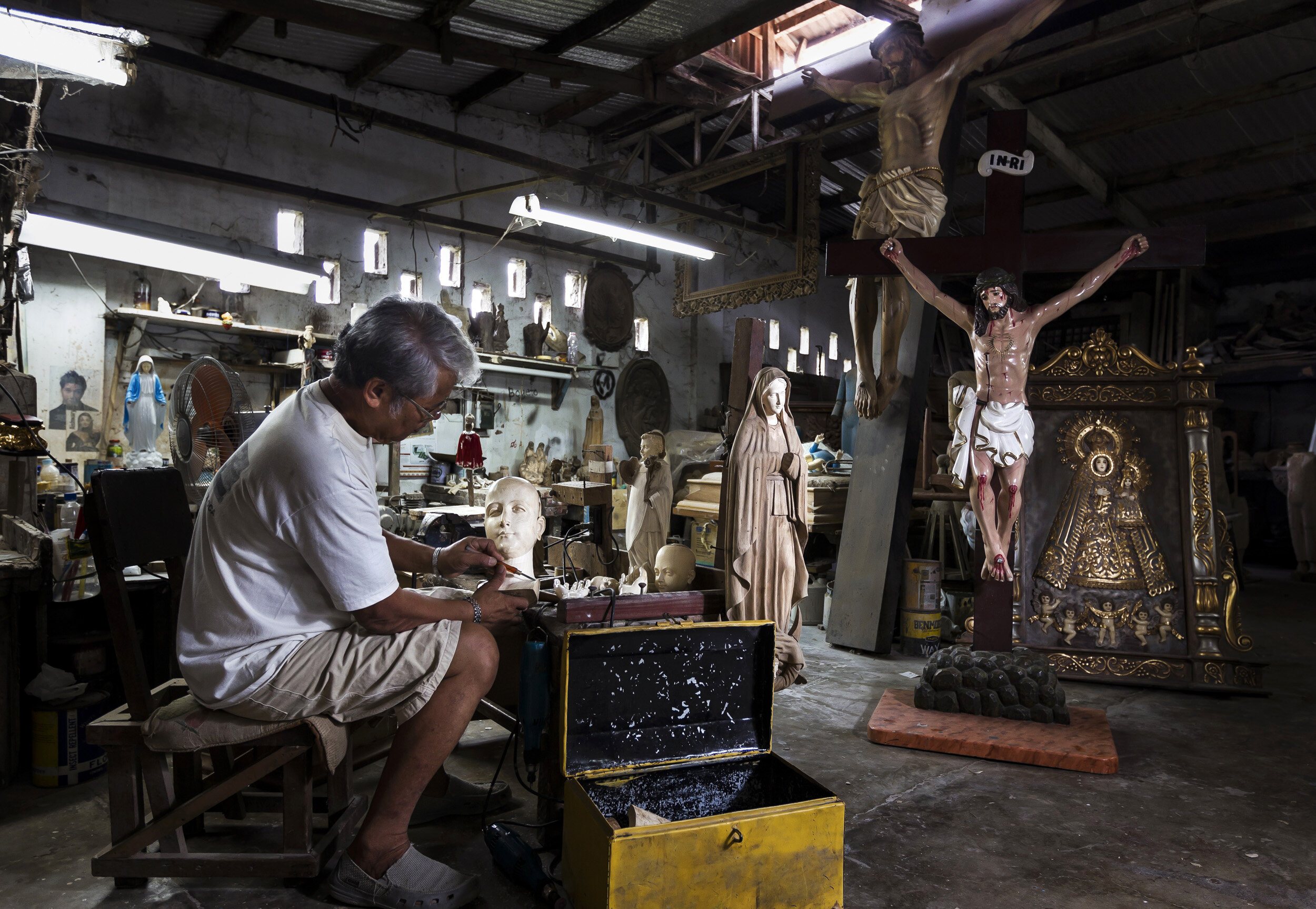VALENZULEA, PHILIPPINES, JANUARY 2012: Master sculptor Marcial Bernales carves an Ivory head and hand set for a Catholic religious icon in his worshop in Valenzulea, close to Manila, Philippines, 25 January 2012. Bernales has been carving Ivory for